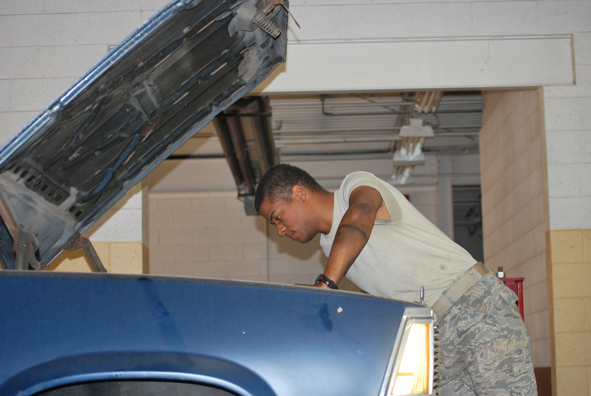 U.S. Air Force Airman 1st Class James Harlequin, 27th Special Operations Communications Squadron infrastructure technician, leans forward under  the hood of his car to check his oil at Cannon Air Force Base, N.M., May 1, 2013. The Basic Car Care Class is one of the manny auto skills clases offerd at the Auto Skills Center. (U.S. Air Force photo/Desiree Ann Montenegro)