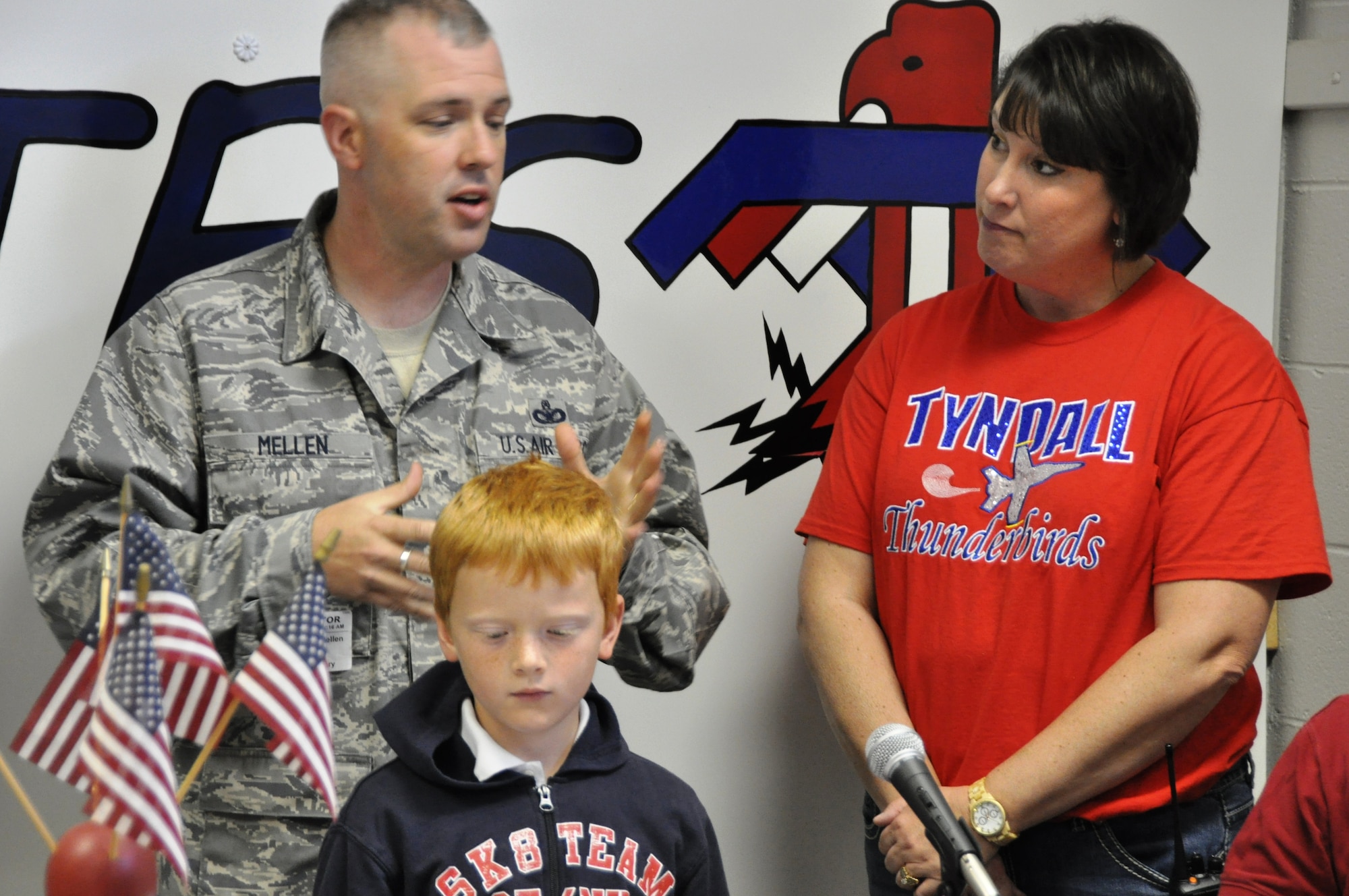 Master Sgt. Michael Mellen, 325th SFS military working dog section kennel master, Mrs. Susan Ross, Tyndall Elementary School principal, and Tyndall Elementary School second-grader Jesse Wolf talk during Tyndall Elementary School’s morning broadcast service, WTES, April 26 at Tyndall Elementary School. Jesse designed the winning T-shirt that will be given away at the 325th SFS Kennel during their demos. (U.S. Air Force photo by Airman 1st Class Alex Echols)