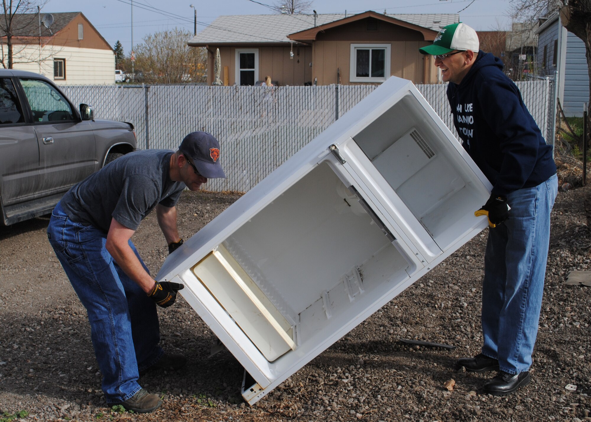 Master Sgt. David Wheeler, 341st Civil Engineer Squadron member (left), and Tech. Sgt. Noel Gonzalez, 341st CES structures member, lift an unwanted refrigerator from an alley way of a Great Falls neighborhood.  Community members were able to put unwanted trash and large items in their alleys so that MApril Cleanup volunteers could pick them up to be transported to a landfill.  (U.S. Air Force photo/Senior Airman Cortney Paxton)