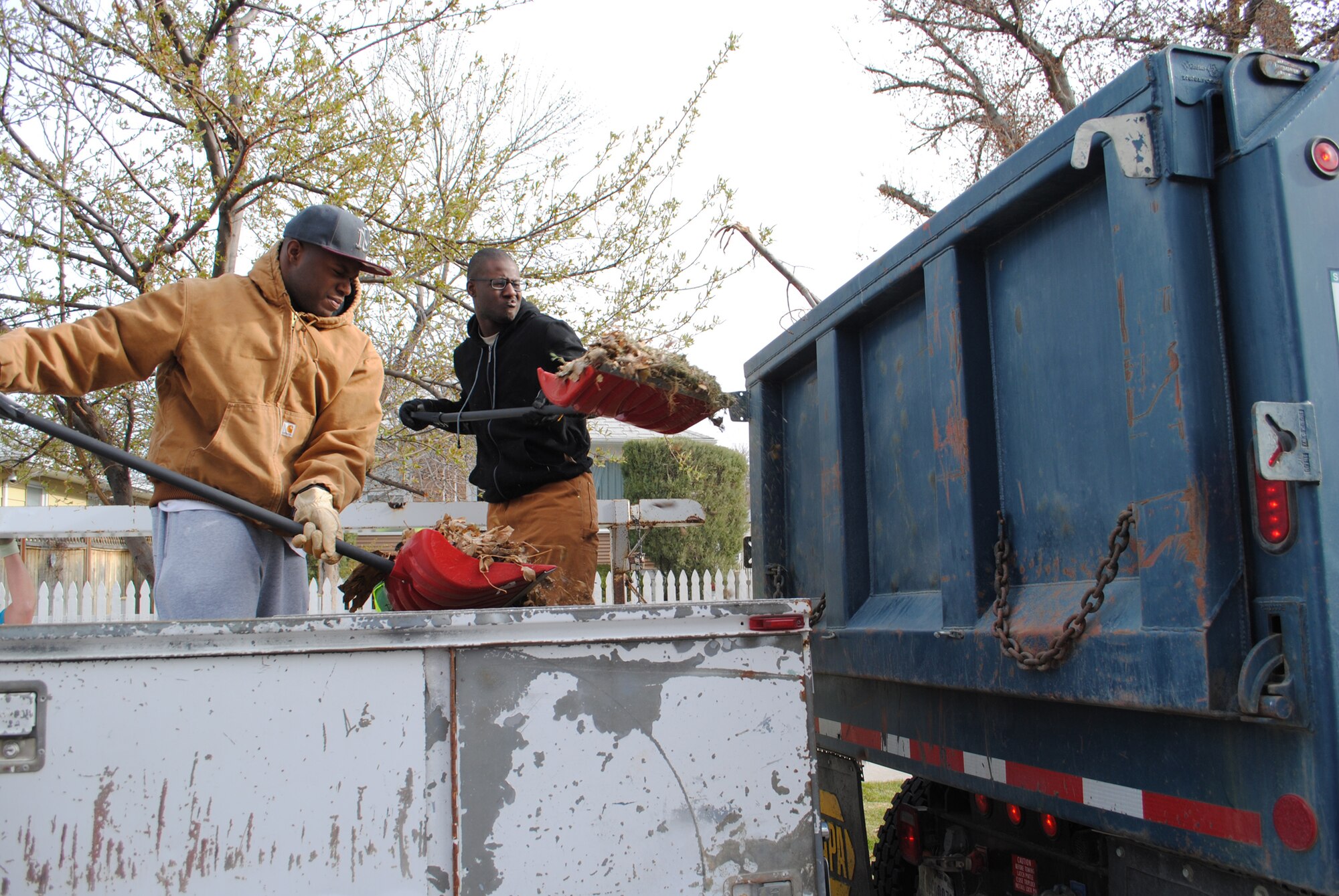 Senior Airmen Ricardo Fredeling, left, and Rashad Pope, both 341st Civil Engineer Squadron pavement and construction equipment apprentices, move leaves and trash from the bed of a truck to a CES dump truck during MApril Cleanup on April 27.  The truck belonged to a Great Falls community member who was unable to drive the vehicle to a landfill.  (U.S. Air Force photo/Senior Airman Cortney Paxton)