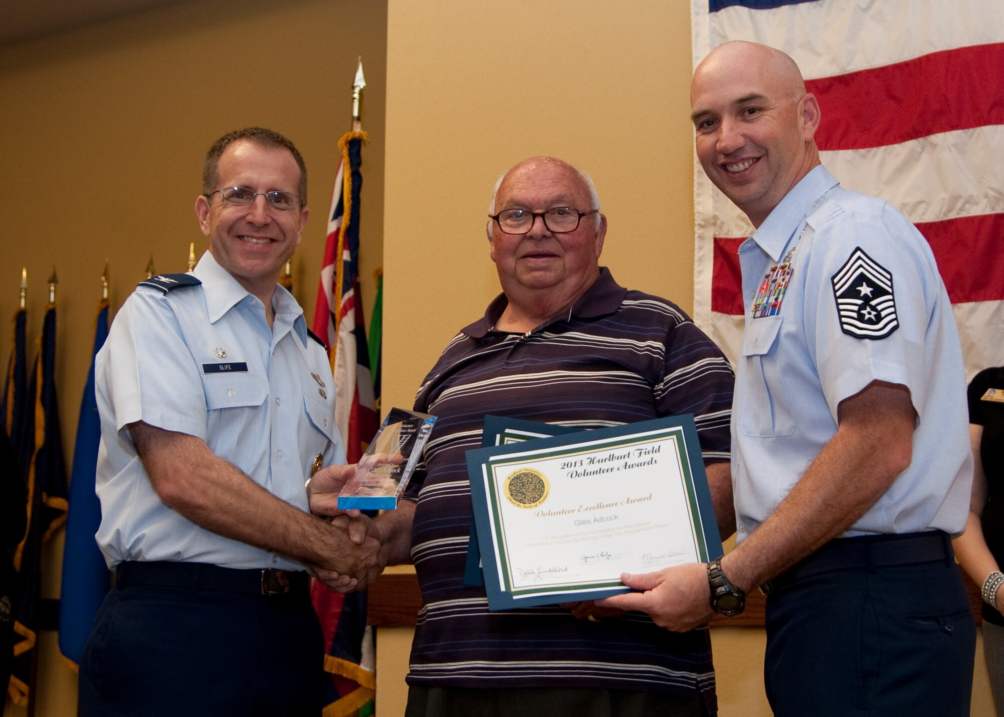 Col. Jim Slife, commander of 1st Special Operations Wing, left, and Chief Master Sgt. Jeffrey Maberry, command chief of 1st SOW, right, present Giles Adcock, Hurlburt Spouses Club, center, with the Volunteer Excellence Award during the annual Volunteer Recognition Ceremony at the Soundside Club at Hurlburt Field, Fla., May 1, 2013. The ceremony recognized 50 individuals and organizations for volunteerism in the Team Hurlburt and Emerald Coast communities in 2012. (U.S. Air Force photo / Airman 1st Class Nigel Sandridge) 