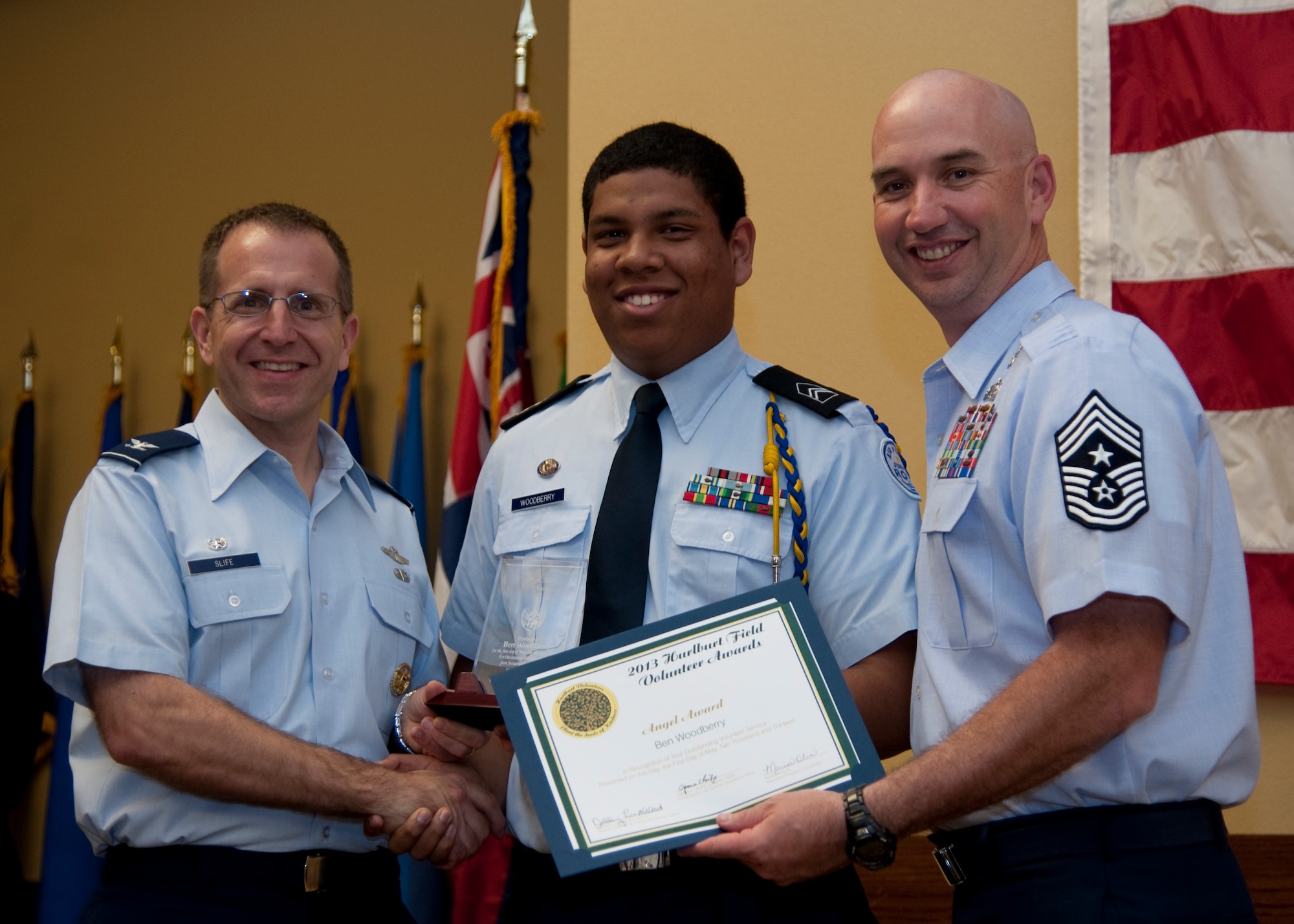 Col. Jim Slife, commander of 1st Special Operations Wing, left, and Chief Master Sgt. Jeffrey Maberry, command chief of 1st SOW, right, present Ben Woodberry, 1st Special Operations Chapel Youth Group, center, with the youth Angel Award during the annual Volunteer Recognition Ceremony at the Soundside Club at Hurlburt Field, Fla., May 1, 2013. The ceremony recognized 50 individuals and organizations for volunteerism in the Team Hurlburt and Emerald Coast communities in 2012. (U.S. Air Force photo / Airman 1st Class Nigel Sandridge) 
