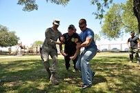 Airman 1st Class John Evans (left) and Staff Sgt. Erik Chittick (right) help Airman 1st Class Devin Fisher to the ground after Fisher was voluntarily tased during a security forces demonstration. (U.S. Air Force photo by Airman 1st Class Lincoln Korver/ Released)