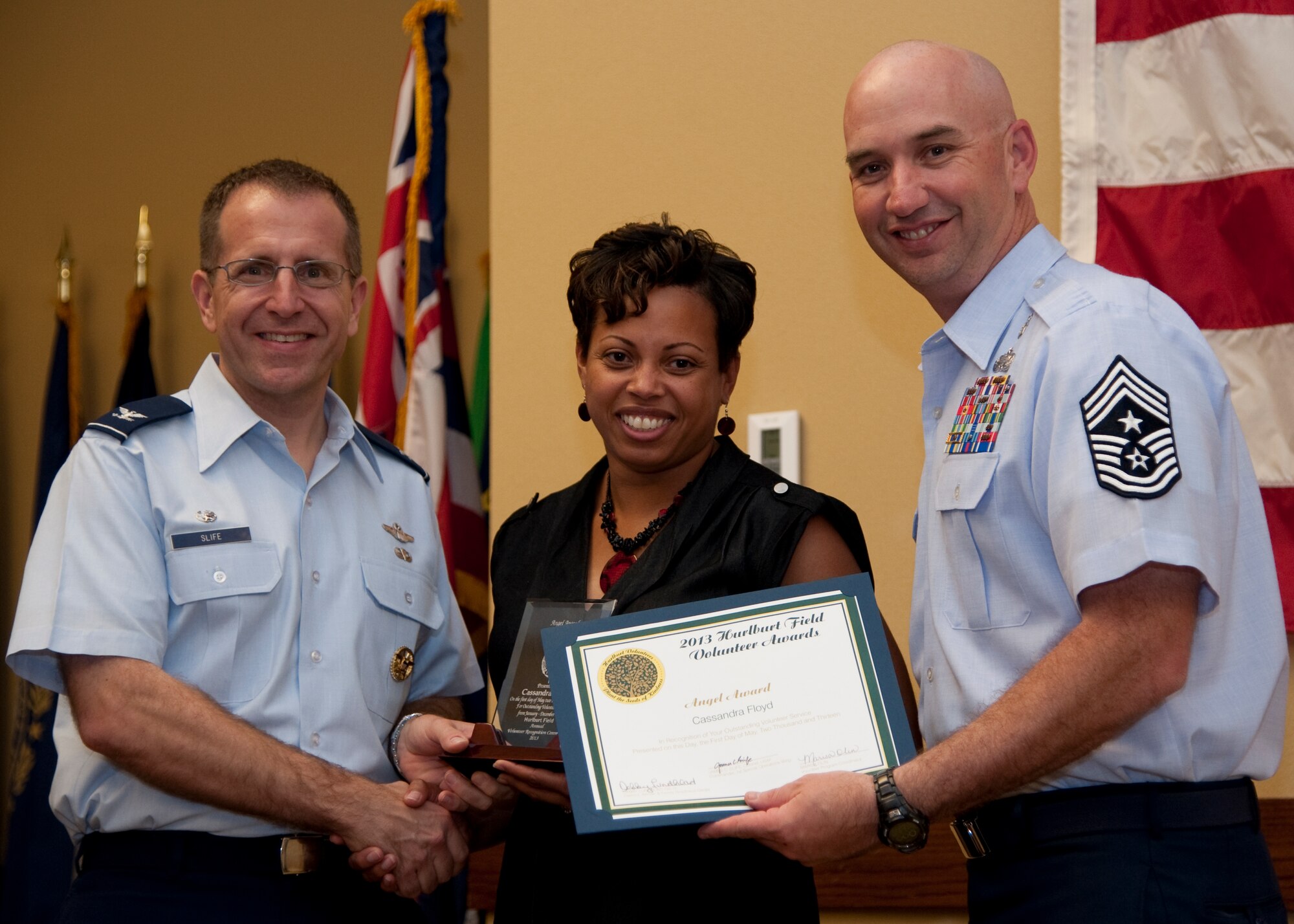 Col. Jim Slife, commander of 1st Special Operations Wing, left, and Chief Master Sgt. Jeffrey Maberry, command chief of 1st SOW, right, present Cassandra Floyd, Hurlburt Spouses Club, center, with the family member Angel Award during the annual Volunteer Recognition Ceremony at the Soundside Club at Hurlburt Field, Fla., May 1, 2013. The ceremony recognized 50 individuals and organizations for volunteerism in the Team Hurlburt and Emerald Coast communities in 2012. (U.S. Air Force photo / Airman 1st Class Nigel Sandridge) 