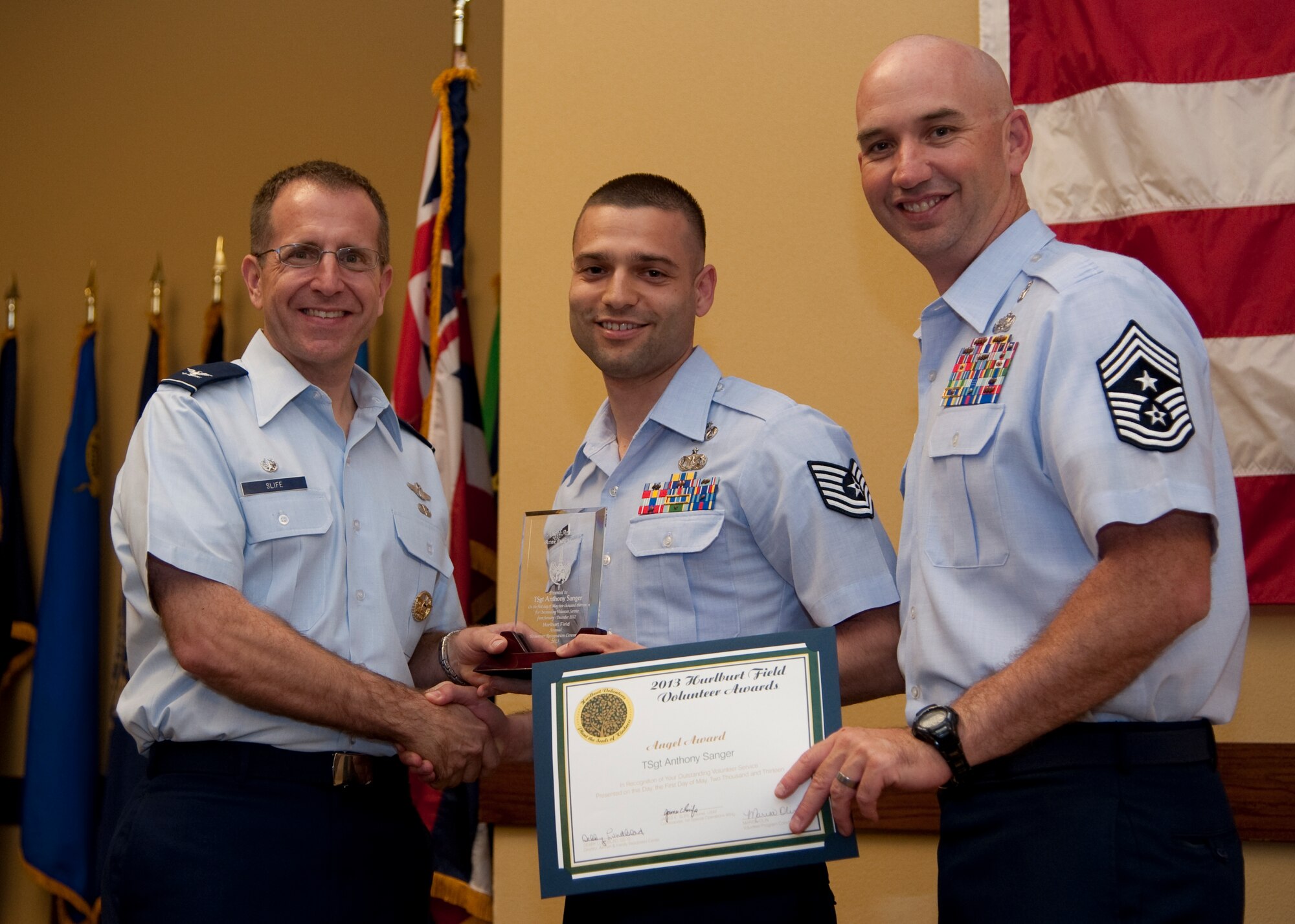 Col. Jim Slife, commander of 1st Special Operations Wing, left, and Chief Master Sgt. Jeffrey Maberry, command chief of 1st SOW, right, present Tech. Sgt. Anthony Sanger, 14th Weapons Squadron, center, with the active-duty Angel Award during the annual Volunteer Recognition Ceremony at the Soundside Club at Hurlburt Field, Fla., May 1, 2013. The ceremony recognized 50 individuals and organizations for volunteerism in the Team Hurlburt and Emerald Coast communities in 2012. (U.S. Air Force photo / Airman 1st Class Nigel Sandridge) 