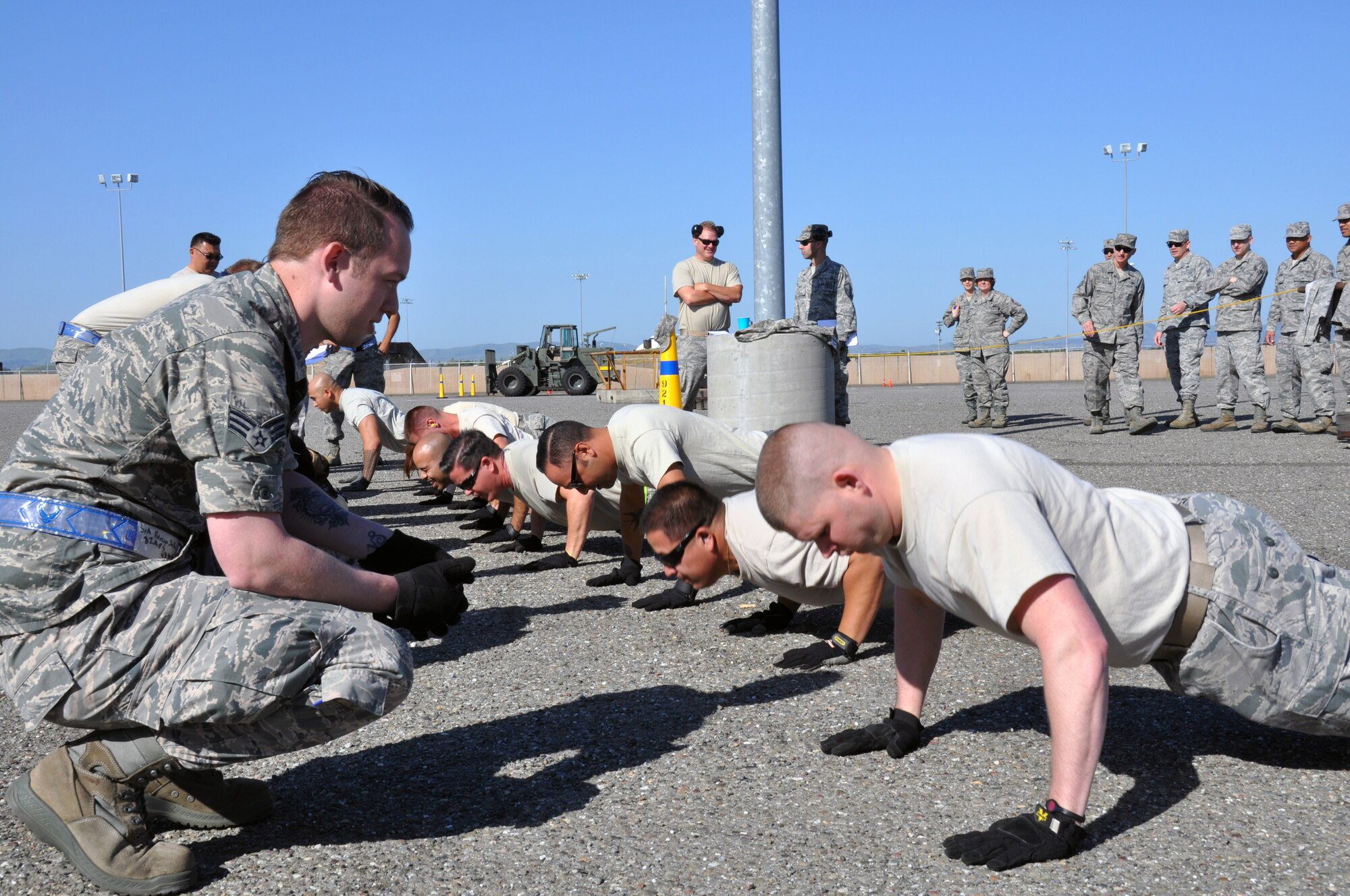 TRAVIS AIR FORCE BASE, Calif. -- Airmen with the 55th Aerial Port Squadron do the maximum amount of push-ups they can within one minute as Airmen with the 82nd Aerial Port Squadron keep count. The activity was part of a team building competition between the two squadrons held on April 21, 2013, which also included 60K Tunner aircraft cargo loader and fork-lift driving. (U.S. Air Force photo / Senior Airman Cindy Alejandrez)