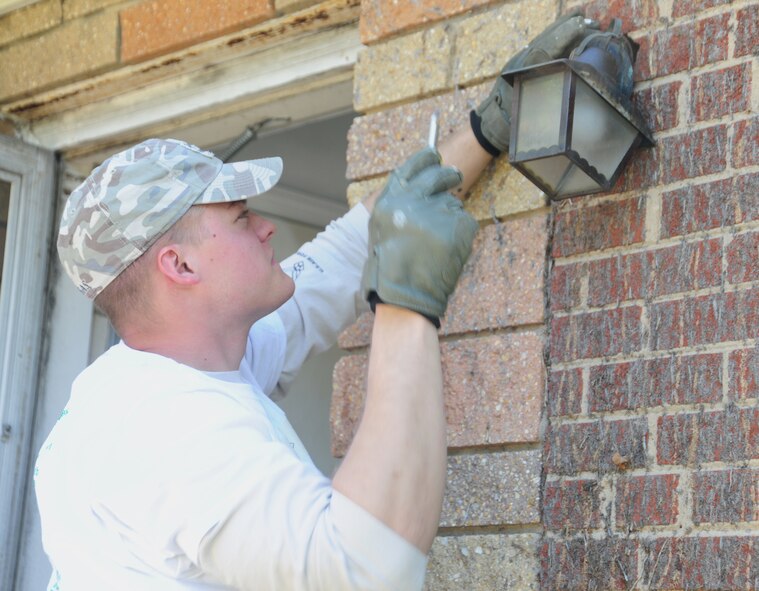 Joint Base Andrews, Md., Airman 1st Class Travis Tierney-Kanning, 11th Civil Engineer Squadron electrician, removes an outdated porch light, April 27, 2013, in a community effort to spruce up homes of low-income, disabled and elderly people.Team Andrews members helped the 25th Christmas in April event. (U.S. Air Force photo/Staff Sgt. Amber Russell)