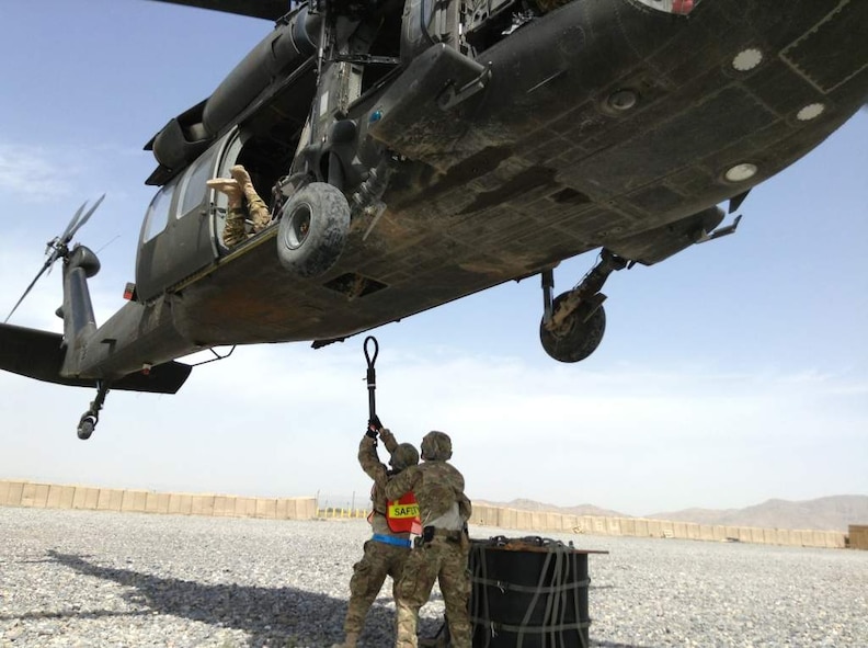 U.S. Air Force Staff Sgt. Shawn Beedham
and U.S. Air Force Senior Airman Joshua Foley, both from the 451st Expeditionary Logistics Readiness Squadron, prepare to hook an 1,800 pound A-22 cargo bag to a UH-60 Black Hawk flown by Soldiers of the 3rd Combat Aviation Brigade during a coalition-joint slingload mission at Kandahar Airfield, Afghanistan. (Courtesy photo)
