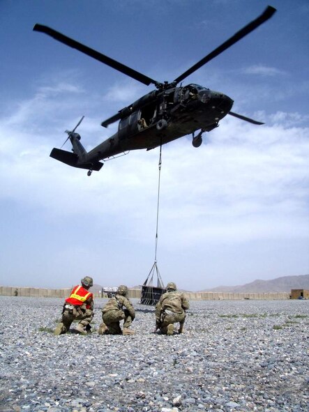 (From left) U.S. Air Force Senior Airman Joshua Foley, U.S. Army Lt. Col. Erica Herzog and U.S. Air Force Tech. Sgt. Terry Beasley, watch as Soldiers of the 3rd Combat Aviation Brigade lift an 1,800 pound A-22 cargo bag they had just hooked up to a UH-60 Black Hawk helicopter during a coalition-joint slingload mission at Kandahar Airfield, Afghanistan. Beasley is deployed from Moody Air Force Base, Ga. (Courtesy photo)