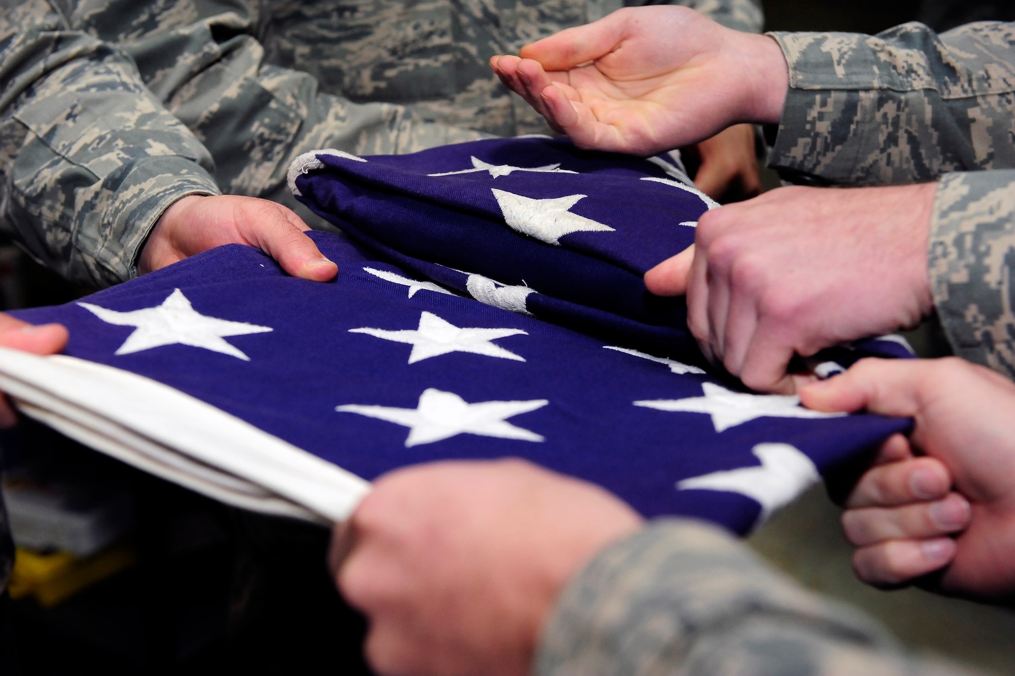 Members of the 509th Bomb Wing Honor Guard A-Team tightly fold a flag during training at Whiteman Air Force Base, Mo., April 23, 2013. Whiteman’s Honor Guard is split into two teams, A-Team and B-Team, each consisting of 22 Airmen.  (U.S. Air Force photo by Airman 1st Class Shelby R. Orozco/Released)