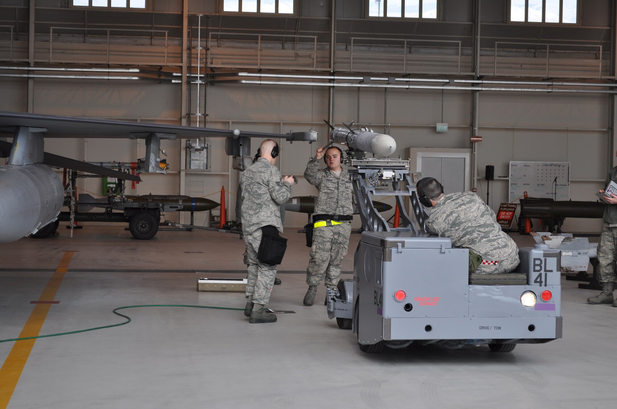 (Left) Staff Sgt. Benjamin Angley, Senior Airmen Carleton Kennedy and Jackie Sanders load a missile onto an aircraft during a quarterly loading competition at Aviano Air Base, Italy. Aircraft maintenance units train consistently to be proficient at their jobs and quarterly loading competitions help evaluate their proficiency. The load crew members are assigned to the 555th Aircraft Maintenance Unit. (Courtesy photo/ Megan Sanders)