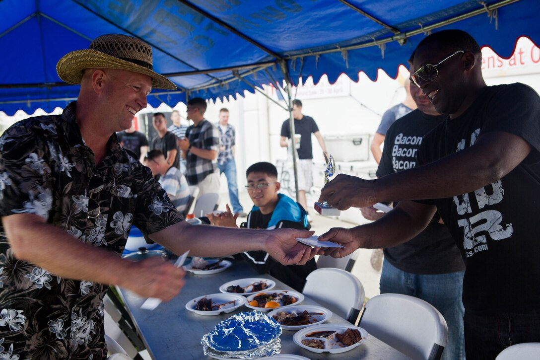 Mark L. Roberts, left, accepts a trophy for best overall barbeque from Master Sgt. Emanuel L. Walker during the 5th annual Camp Hansen barbecue cook-off outside the Post Exchange April 27. Roberts was also awarded a trophy for best brisket. Roberts is the camp director of Camp Hansen and participated in the cook-off. Walker is the manager of the III Marine Expeditionary Force mess hall, III MEF Headquarters Group, and was a judge for the cook-off. Photo by Pfc. Kasey Peacock 