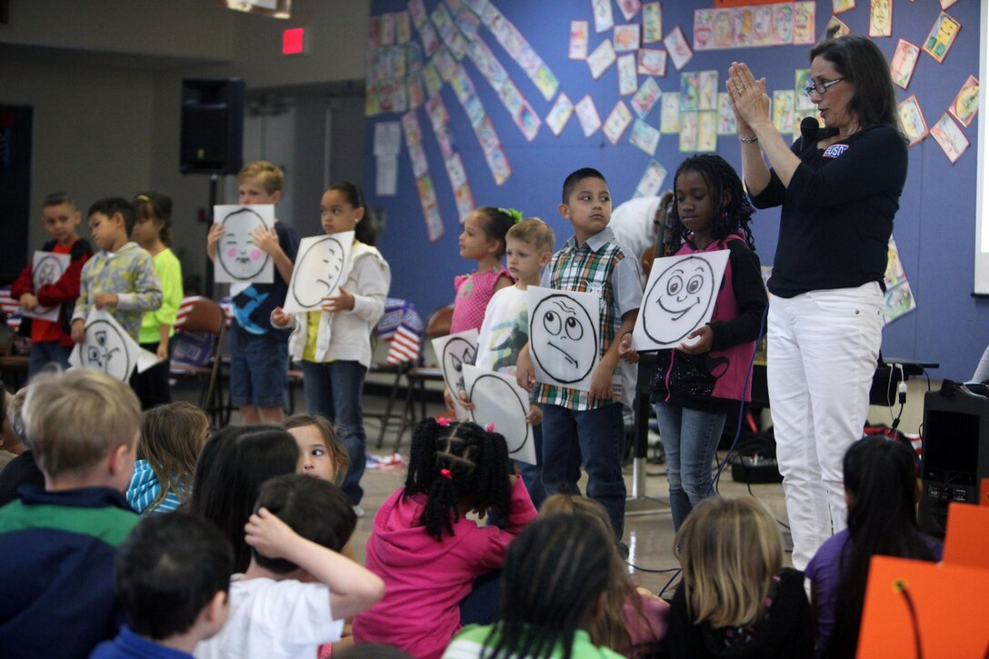 Debbie Fink signs the word “ask” during her presentation at Zukeran Elementary School on Camp Foster April 23. She also explained how everyone reacts differently to the same situation and told them that each emotion is okay and children can ask for help if they are ever overwhelmed. Fink is the co-author of “Little C.H.A.M.P.S.: Child Heroes Attached to Military Personnel,” and visited the school during an Asia-Pacific tour with the USO. (U.S. Marine Corps photo by Cpl. Alyssa N. Gunton/ Released)