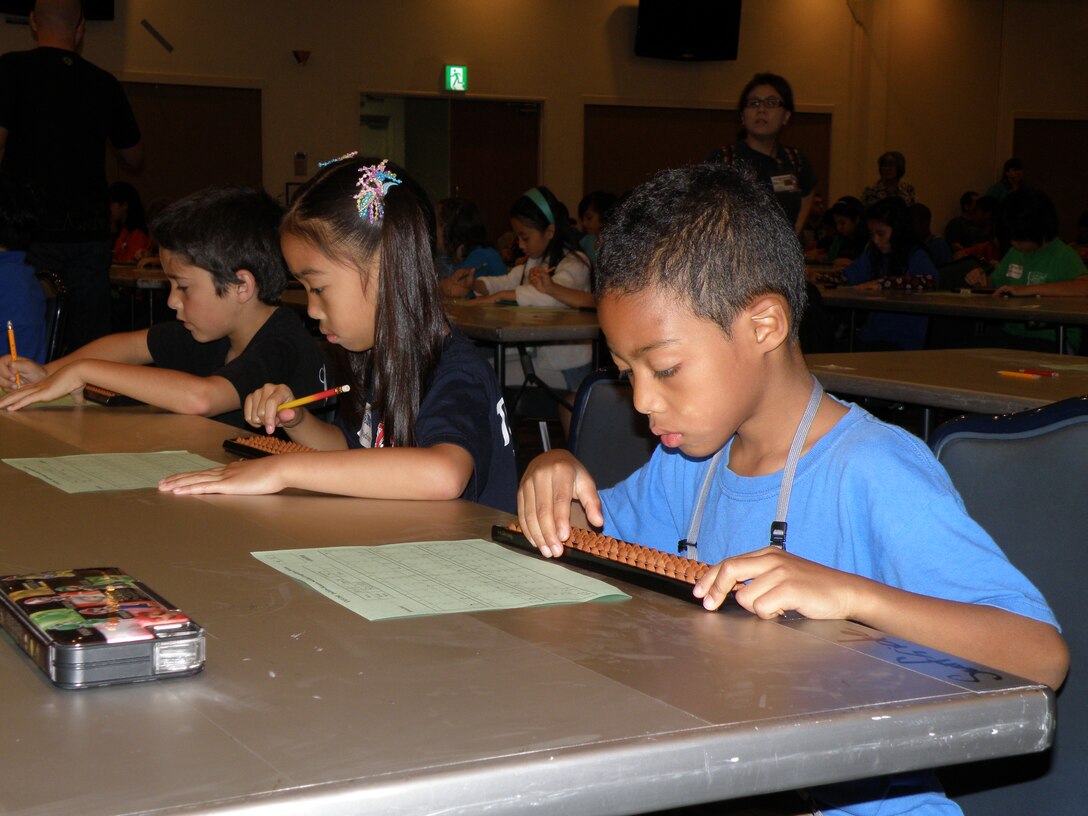 Myles Simpson, right, a first-grade student at Bechtel Elementary School, solves a math problem during the 14th annual soroban contest April 29 at Camp Kinser. More than 150 students competed for first place in oral and written examinations.