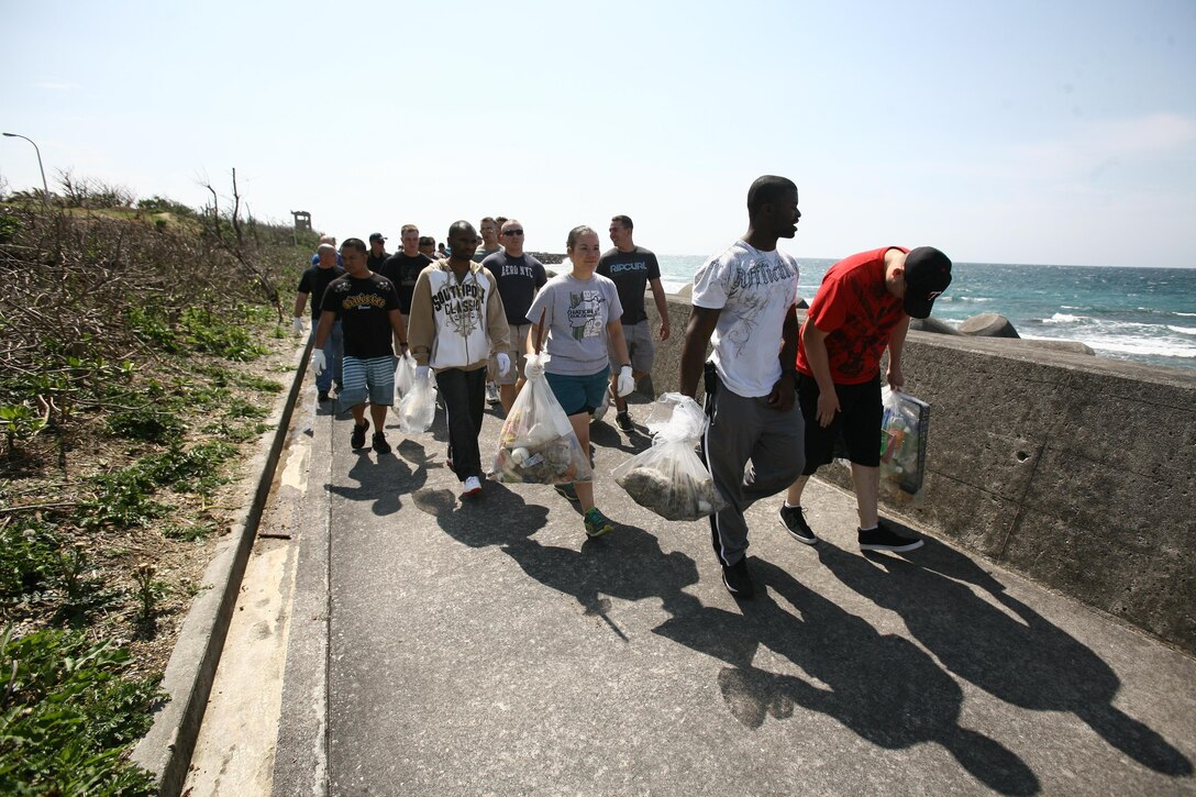 Marines and sailors carry trash to a collection point during the Tropical Beach and seawall cleanup April 26 in Ginowan City. The service members gave their time to clean up the seawall as part of Earth Week.