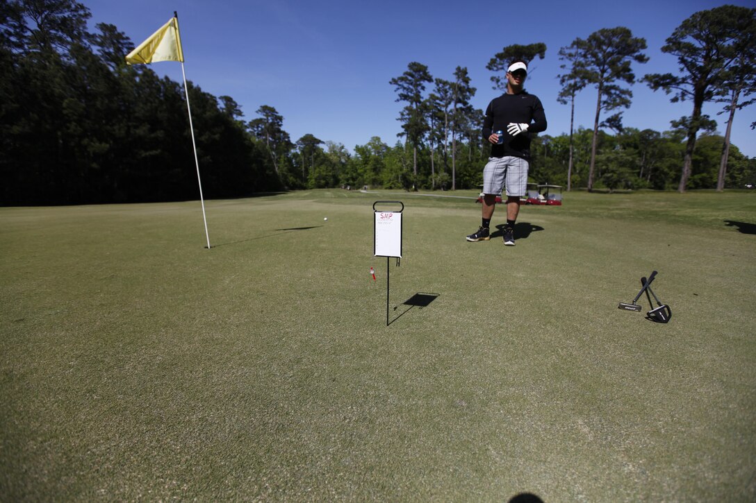 Cpl. Kevin Lagrutta, a data network specialist and cyber network technician with Marine Wing Communications Squadron 28, checks Cpl. Kyle Schmidt's, a data network specialist and cyber network technician with MWCS-28, drive to see if it was in fact the closest shot to the pin in a sub competition of the Devil Dog Open at the Sound of Freedom golf course April 27. 