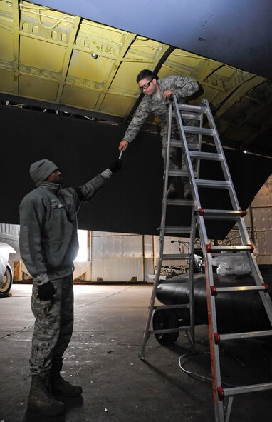 Senior Airman John Hunt, 2nd Maintenance Squadron Accessories Flight Fuels Maintenance, hands tools to Senior Airman Michael Mazolla, 2 MXS Accessories Flight Fuels Maintenance, during the fuel systems of a B-52H Stratofortress on Barksdale Air Force Base, La., May 3, 2013. The Airmen were attaching hoses to the fuel tanks to drain them prior to repairing leaks. (U.S. Air Force photo/Airman 1st Class Andrew Moua)