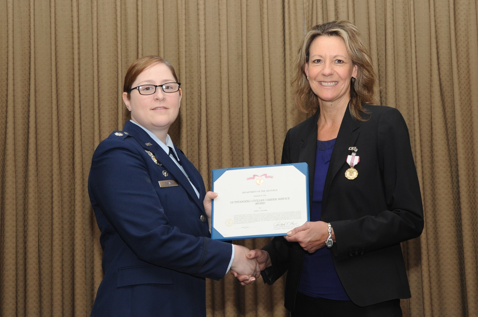 Lt. Col. Sara Deaver, commander 319th Civil Engineer Squadron, presents Mary Giltner, 319th CES deputy base civil engineer, with an Outstanding Civilian Career Service Award during a retirement ceremony, which took place May 3, 2013, on Grand Forks Air Force Base, N.D. Giltner retired after serving 32 years of federal service. (U.S. Air Force photo/Staff Sgt. Amanda Grabiec)