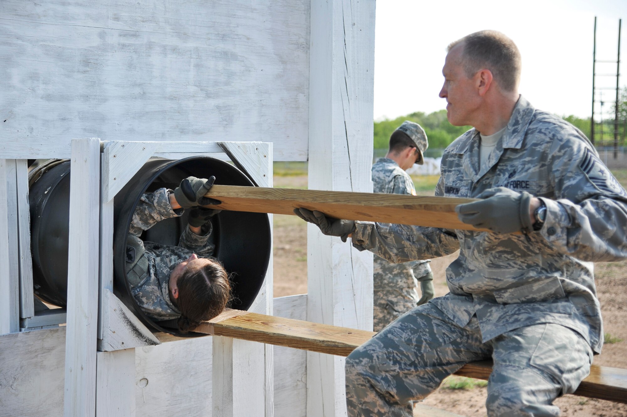 GOODFELLOW AIR FORCE BASE, Texas-- Army Lt. Col. Devon Blake, 344th Military Intelligence Battalion Commander, hands  Chief Master Sgt. Scott Lumpkin, 17th Training Wing Command Chief, a wooden plank during the Leadership Reaction Course April 30. The course is designed to help individuals discover leadership qualities and develop teamwork by completing obstacles. (U.S. Air Force photo/ Airman 1st Class Michael Smith)