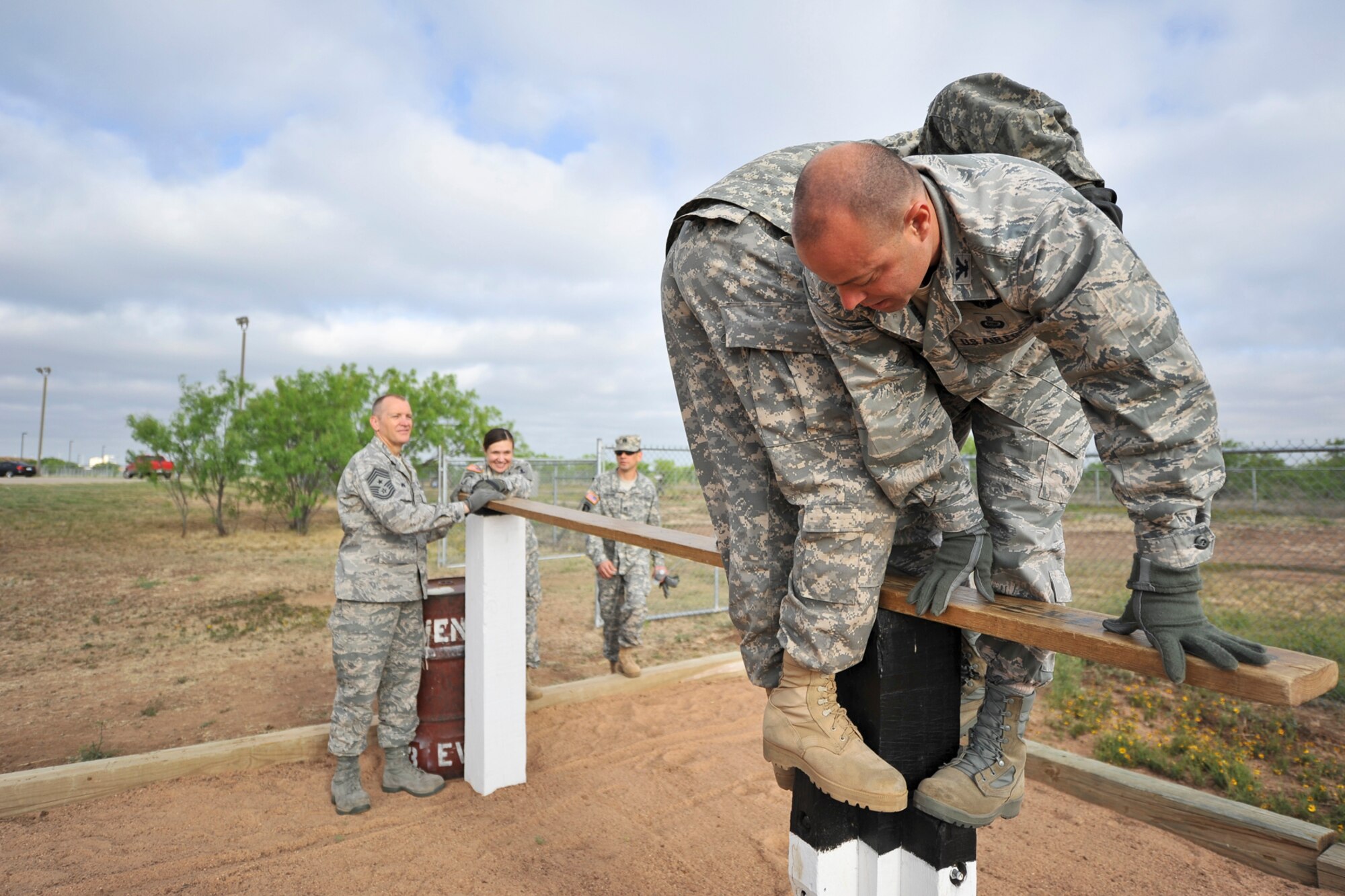 GOODFELLOW AIR FORCE BASE, Texas-- Col. Mark Damiano, 17th Training Wing Commander, holds down a wooden plank while participating in the Leadership Reaction Course April, 30. To complete the obstacle, the team is required to get a barrel across three posts using planks. (U.S. Air Force photo/ Airman 1st Class Michael Smith)