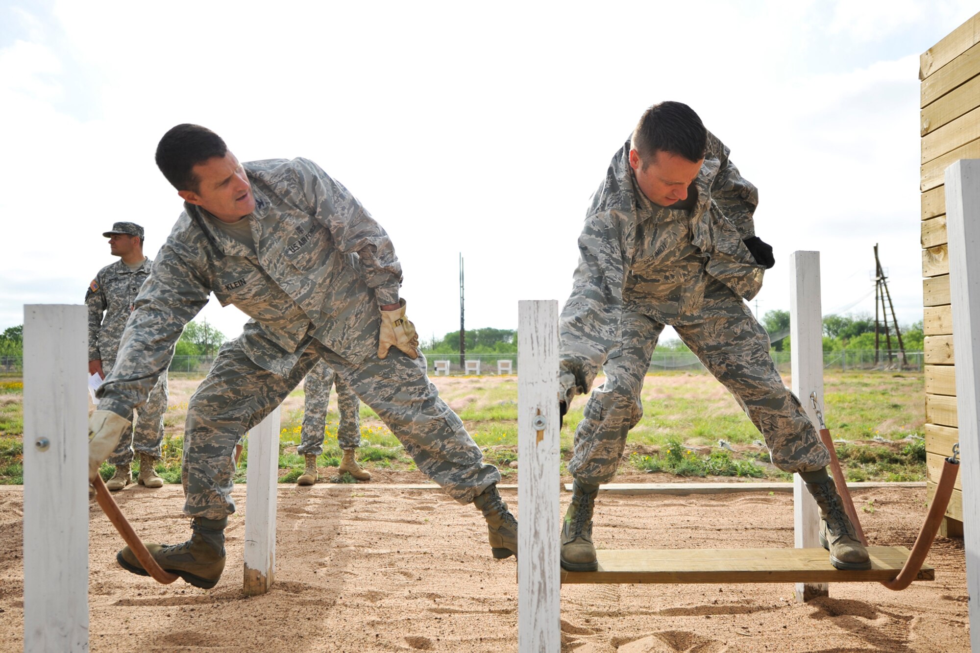 GOODFELLOW AIR FORCE BASE, Texas-- Col. Kelly Klein, 17th Medical Group Commander, and Col. Thomas Schmidt, 17th Training Wing Vice Commander, regain their balance atop chains while participating in the Leadership Reaction Course April 30. To complete this obstacle, the team must get a weighted ammo box and everyone across the simulated river. (U.S. Air Force photo/ Airman 1st Class Michael Smith)