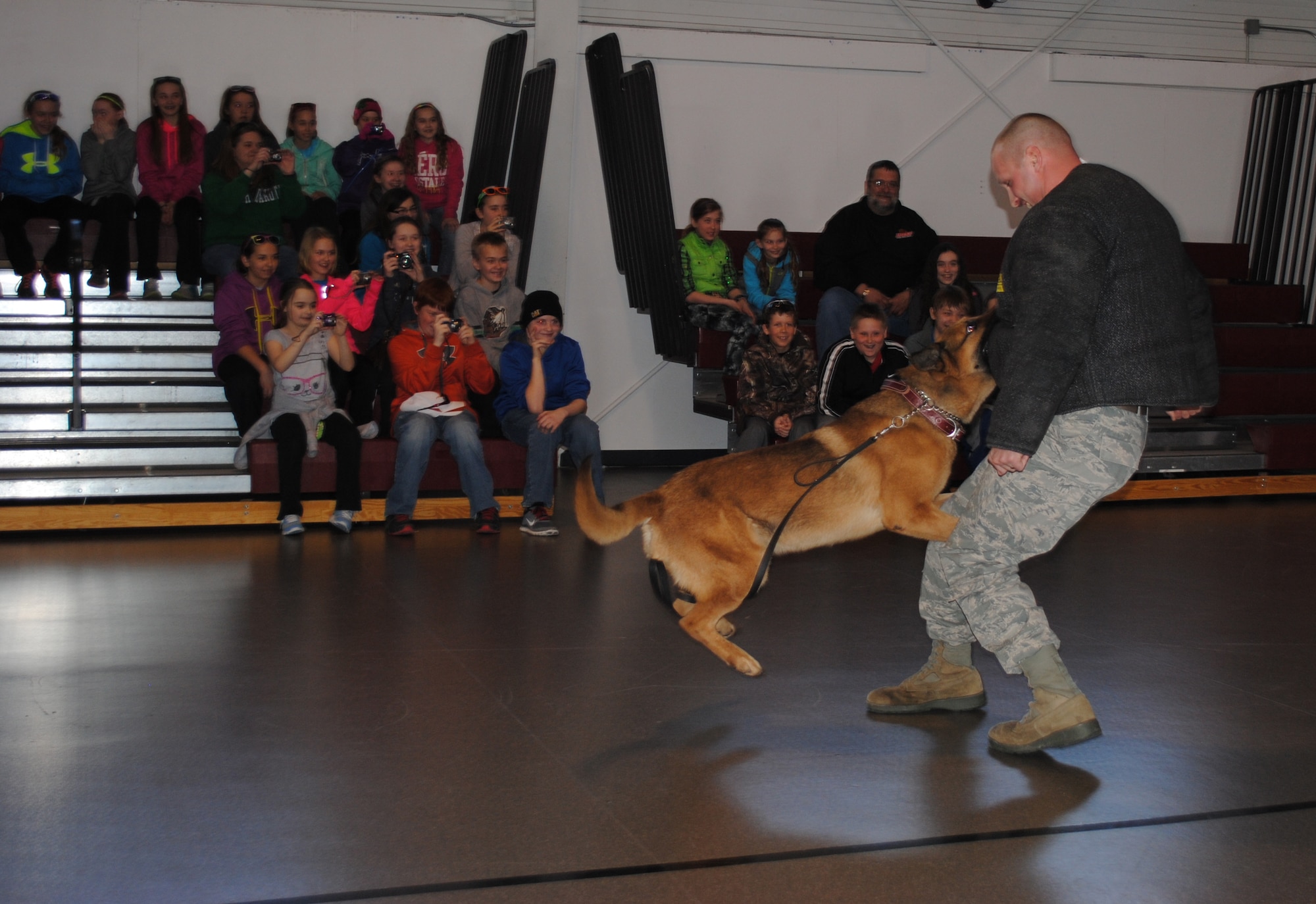 Students and chaperones from St. Joseph’s Catholic School in Devils Lake, N.D., watch as an Air Force K-9 jumps into action and tries to take down 319th Security Forces Squadron kennel master, Staff Sgt. Daniel Carpenter, during a military working dog demonstration April 26, 2013 at Grand Forks Air Force Base, N.D.  Grand Forks AFB offers base tours each Friday from March through November. (U.S. Air Force photo/Staff Sgt. Luis Loza Gutierrez)
