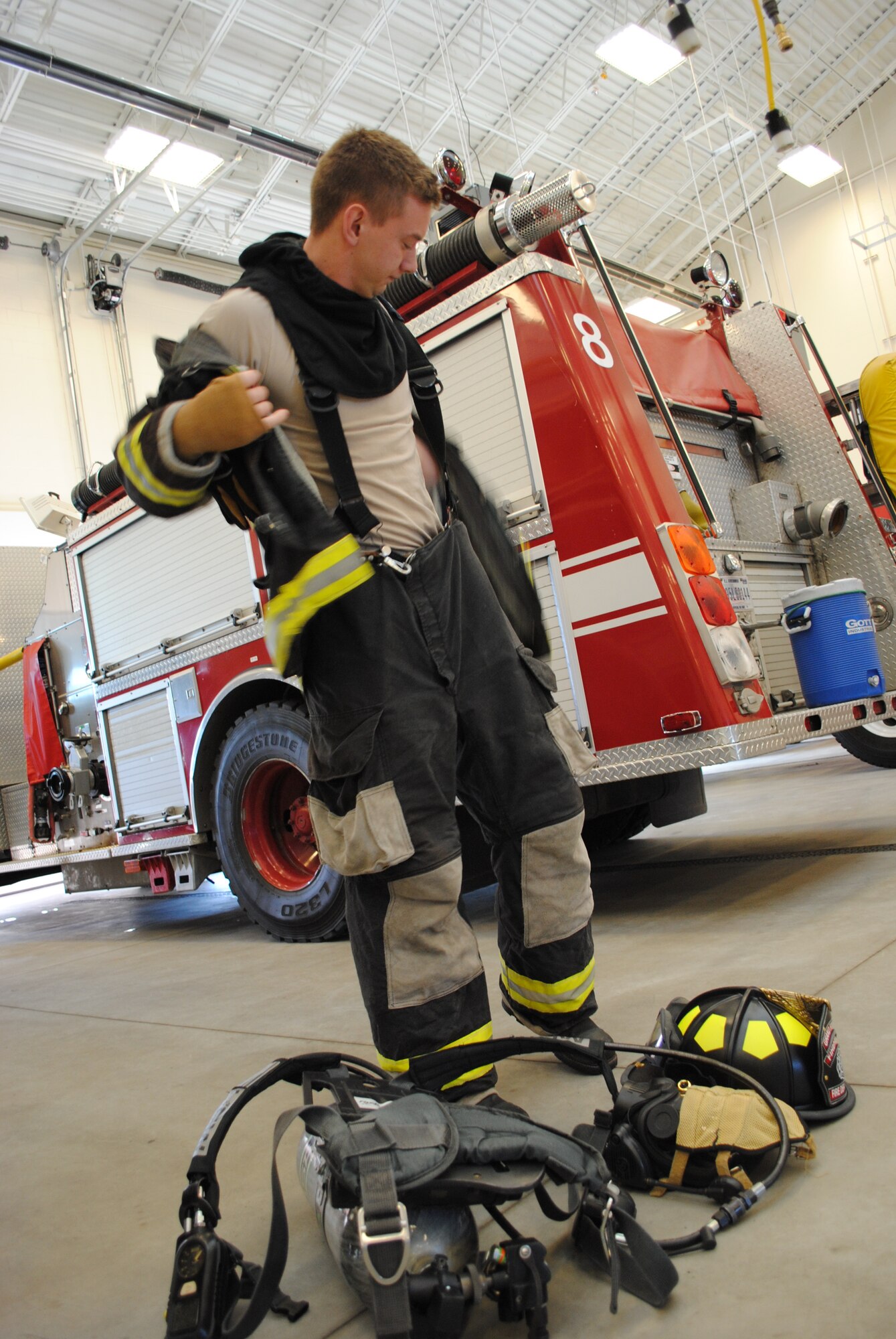 Airman Scott Miller, 319th Civil Engineer Squadron, shows guests how to properly put on firefighting equipment during a base tour by students and chaperones from Devils Lake, N.D., on April 26, 2013. Grand Forks Air Force Base offers base tours each Friday from March through October. (U.S. Air Force photo/Staff Sgt. Luis Loza Gutierrez)