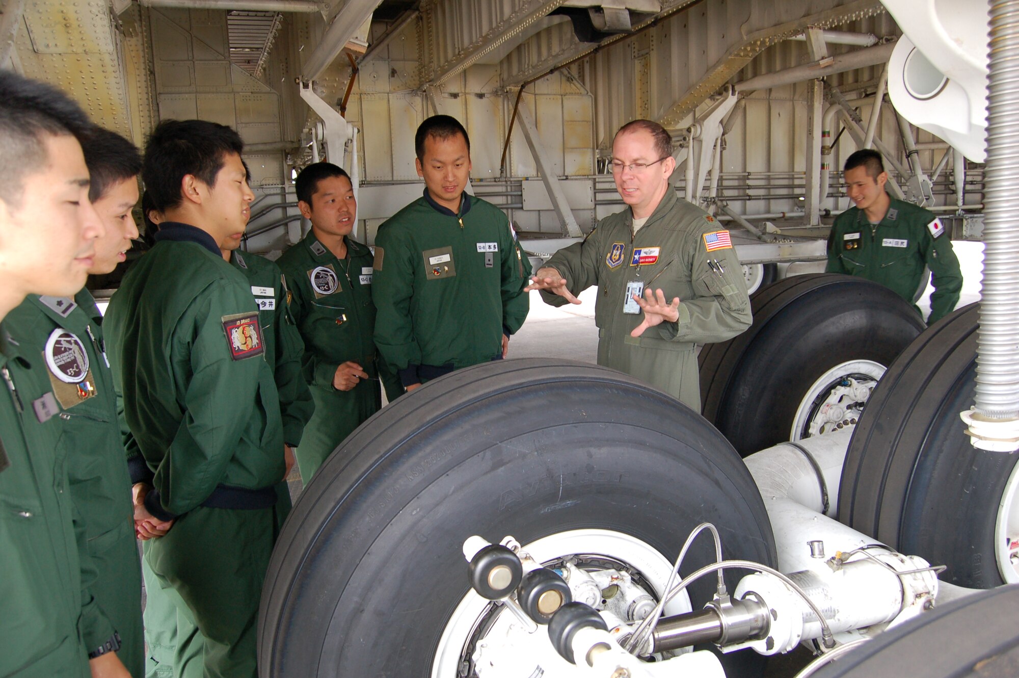 Maj. Chris Garnett, second from right, C-5A Galaxy pilot, explains the jet's complex landing-gear system to visiting pilots from the world-famous Defense Language Institute-English Language Center, located at Joint Base San Antonio-Lackland. Fourteen DLIELC pilots--who hailed from Argentina, Colombia, Ecuador, Honduras, Japan, and Paraguay--used their newly-acquired aviation skills when they visited the 433rd Airlift Wing for a walk-through tour of a wing C-5A Galaxy. ( U.S. Air Force photo by Elsa Martinez)
