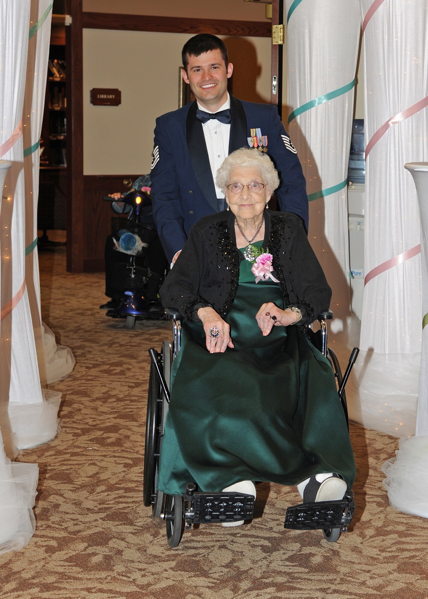 Tech. Sgt. Elliot O’Claire, 69th Reconnaissance Group, guides Alma Melhouse into the ballroom during the Annual Senior Prom Grand March at Woodside Village Valley Memorial Home, April 26, 2013, in Grand Forks, N.D. Eight Airmen from Grand Forks Air Force Base, N.D., escorted 75 residents to their Senior Prom that day.  (U.S. Air Force photo/Airman 1st Class Ashley Nicole Taylor)