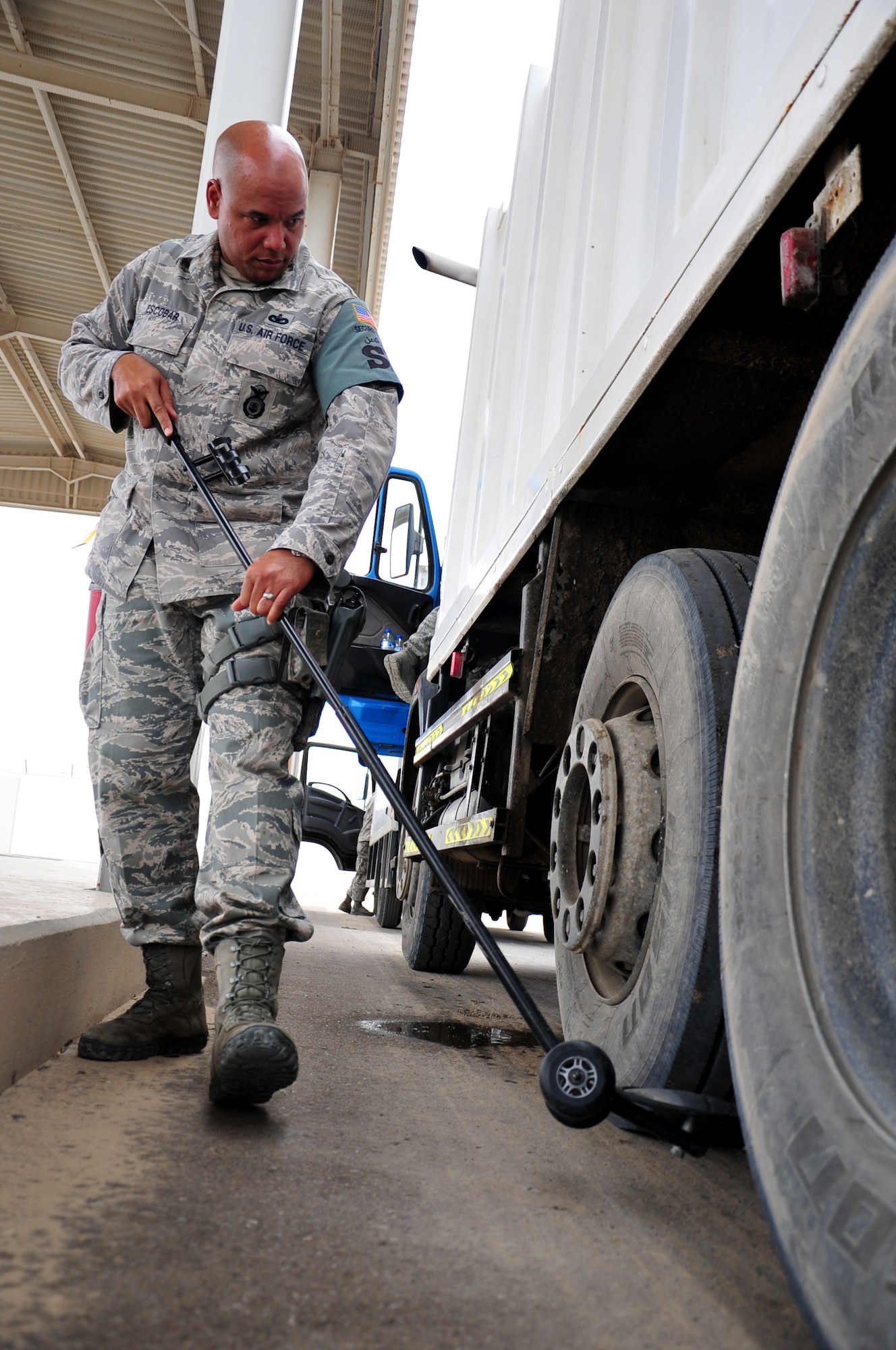 U.S. Air Force Staff Sgt. Luis Escobar, 380th Expeditionary Security Forces Squadron vehicle search area assistant flight chief, uses a mirror to check the underside of a large truck during a search April 30, 2013. 380 ESFS "defenders" provide 24/7 security for base assets and personnel. Escobar is a deployed member of Puerto Rico Air National Guard and is a native of San Juan, Puerto Rico. (U.S. Air Force photo by Staff Sgt. Timothy Boyer)