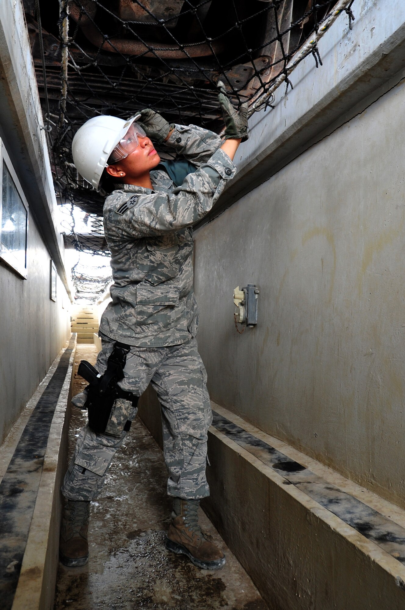 U.S. Air Force Senior Airman Arlene Berker, 380th Expeditionary Security Forces Squadron vehicle search area member checks the undercarriage of a vehicle during an inspection April 30, 2013. 380 ESFS "defenders" provide 24/7 security for base assets and personnel. Berker is deployed from Nellis Air Force Base, Nev., and is a native of Mundelien, Ill. (U.S. Air Force photo by Staff Sgt. Timothy Boyer)