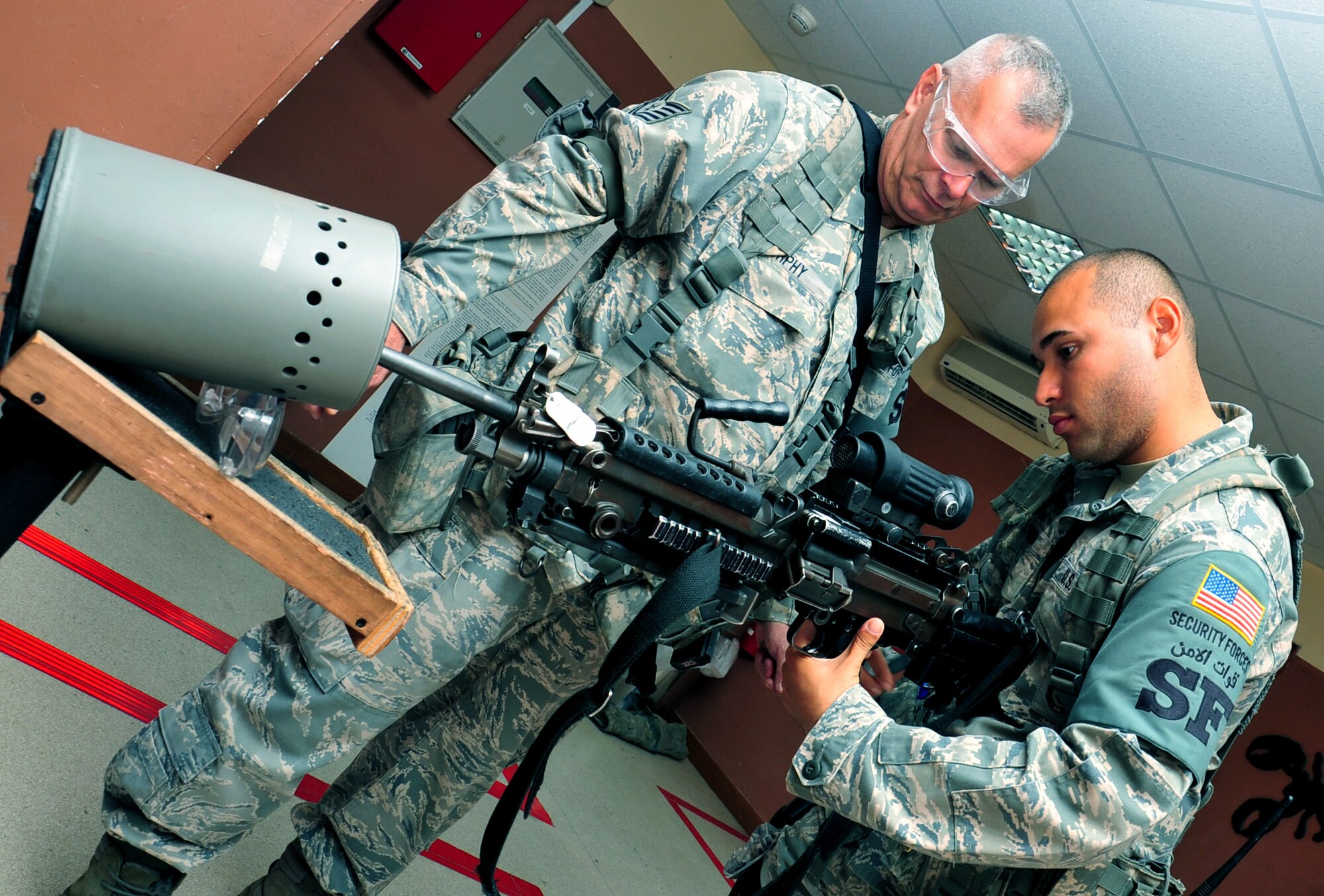 U.S. Air Force Tech. Sgt. Patrick Murphy, 380th Expeditionary Security Forces Squadron member and Aiken, S.C. native, ensures safety as Senior Airman Jon Rivera-Calderon, 380 ESFS member, clears his M-249 automatic rifle as he begins his 12-hours shift April 30, 2013. 380 ESFS "defenders" provide 24/7 security for base assets and personnel. (U.S. Air Force photo by Staff Sgt. Timothy Boyer) 