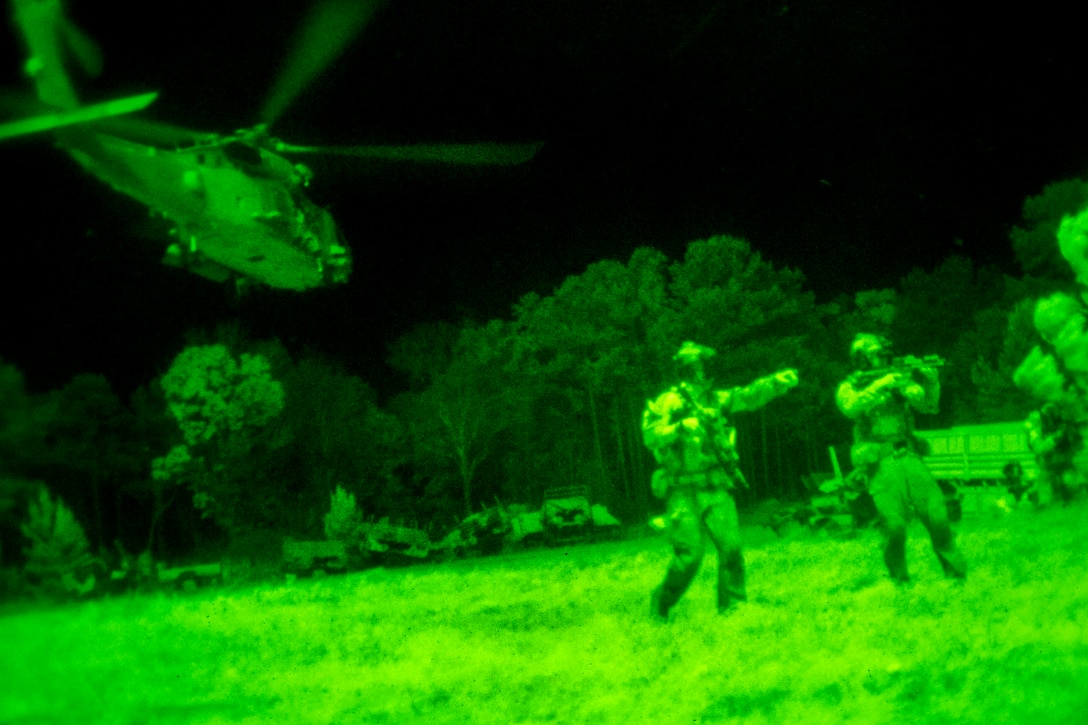 As seen through a night-vision device, a helicopter lifts off as Navy SEALs attack a simulated enemy threat during Operation Urban Corkscrew, part of Emerald Warrior 2013, on Camp Shelby, Miss., April 29, 2013. The SEALs extracted two simulated downed helicopter pilots and returned them to safety during the operation.