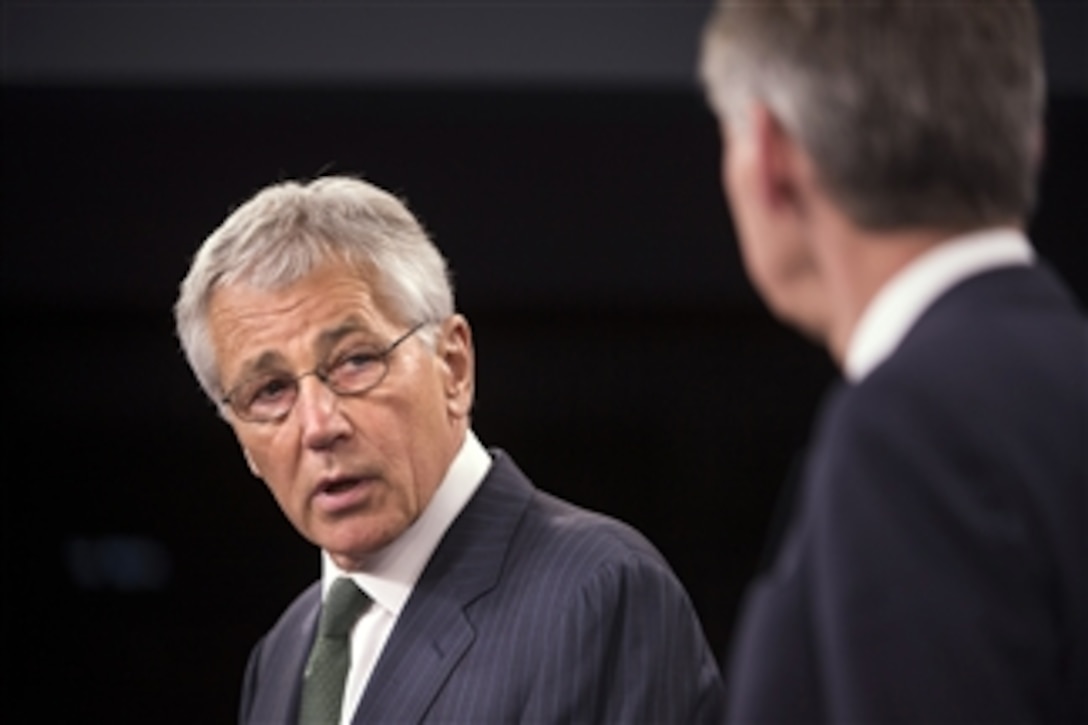 Secretary of Defense Chuck Hagel looks at the United Kingdom's Secretary of State for Defence Phillip Hammond as he describes their earlier meeting to reporters during the opening of a joint press conference in the Pentagon on May 2, 2013.  Hagel and Hammond met earlier to discuss the situations in Syria, Iran and Afghanistan.  