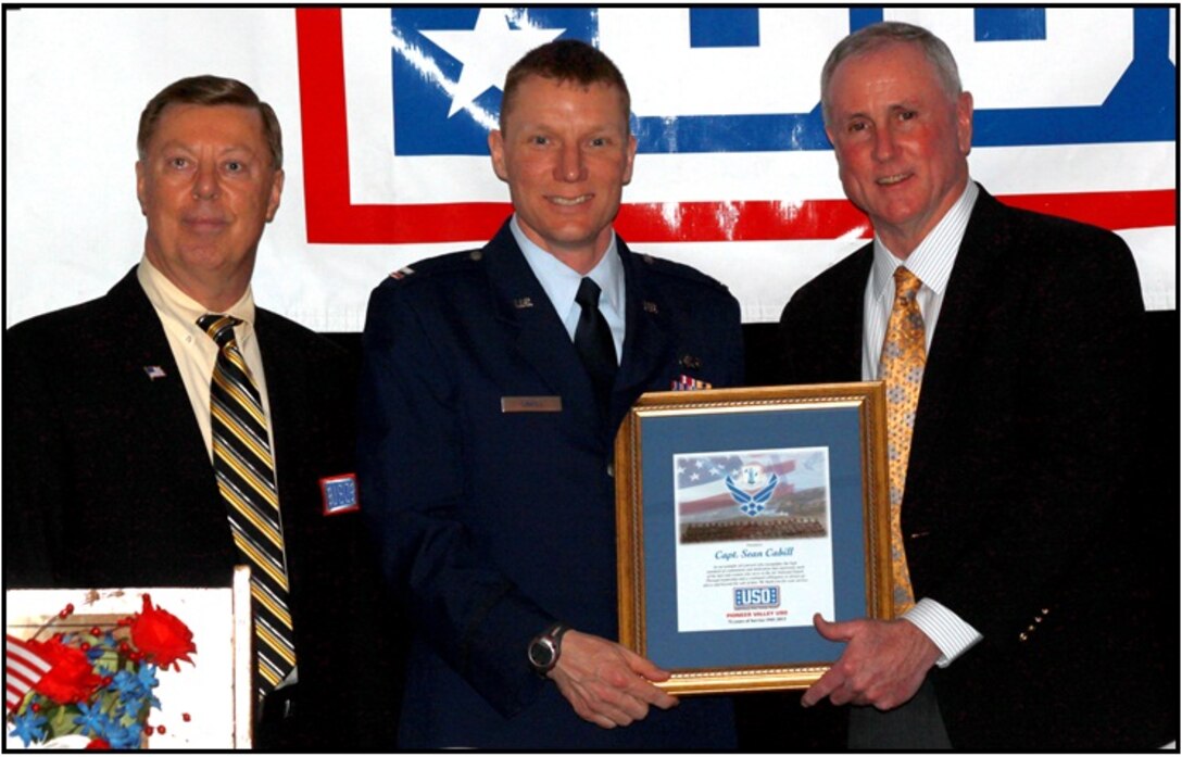 Mr. David Jubinville, the USO Board President stands with Capt. Cahill as Col. Tillman (ret)  presents the award. (Photograph by USO photographer Mr. Tom Overlock)
