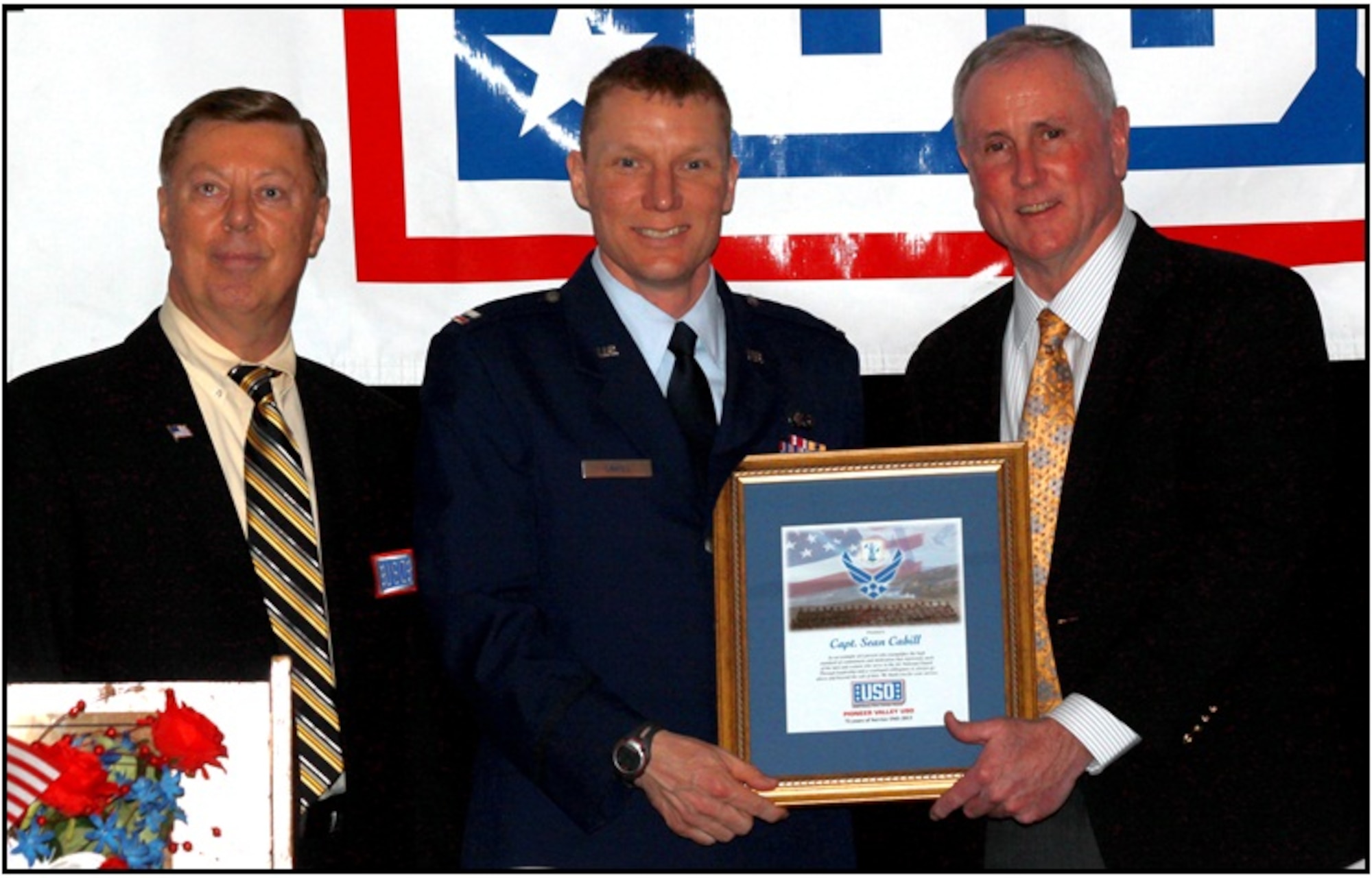 Mr. David Jubinville, the USO Board President stands with Capt. Cahill as Col. Tillman (ret)  presents the award. (Photograph by USO photographer Mr. Tom Overlock)
