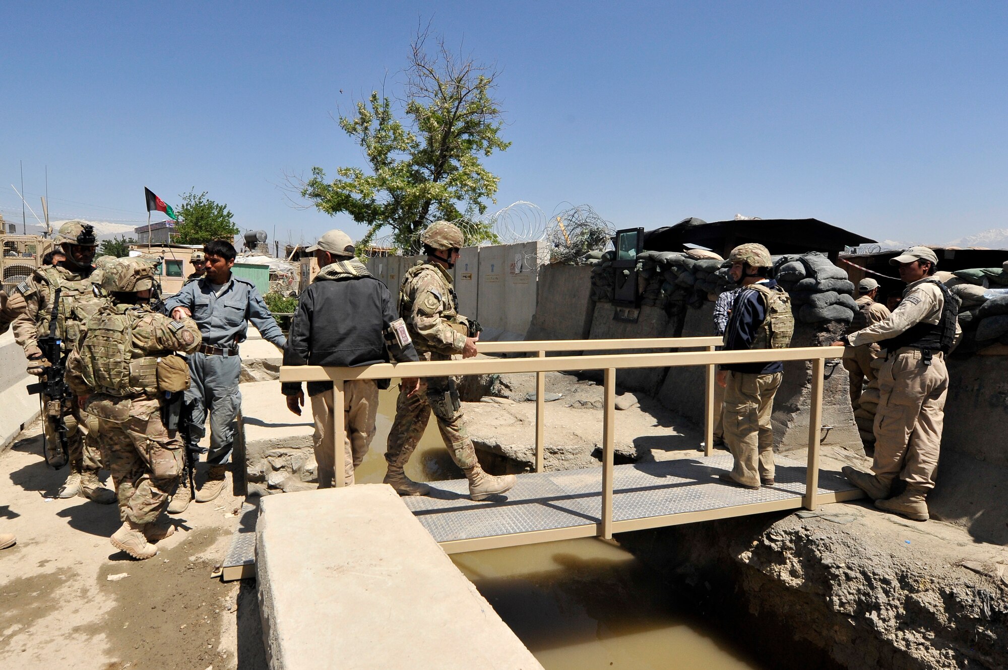 Airmen and local Afghan employees cross the newly installed bridges to Bagram Airfield, Afghanistan, May 2, 2013.  The bridges were requested by the 455th Expeditionary Security Forces Squadron entry point controllers to provide safe passage to and from BAF for the airfield employees. (U.S. Air Force photo/Senior Airman Chris Willis)