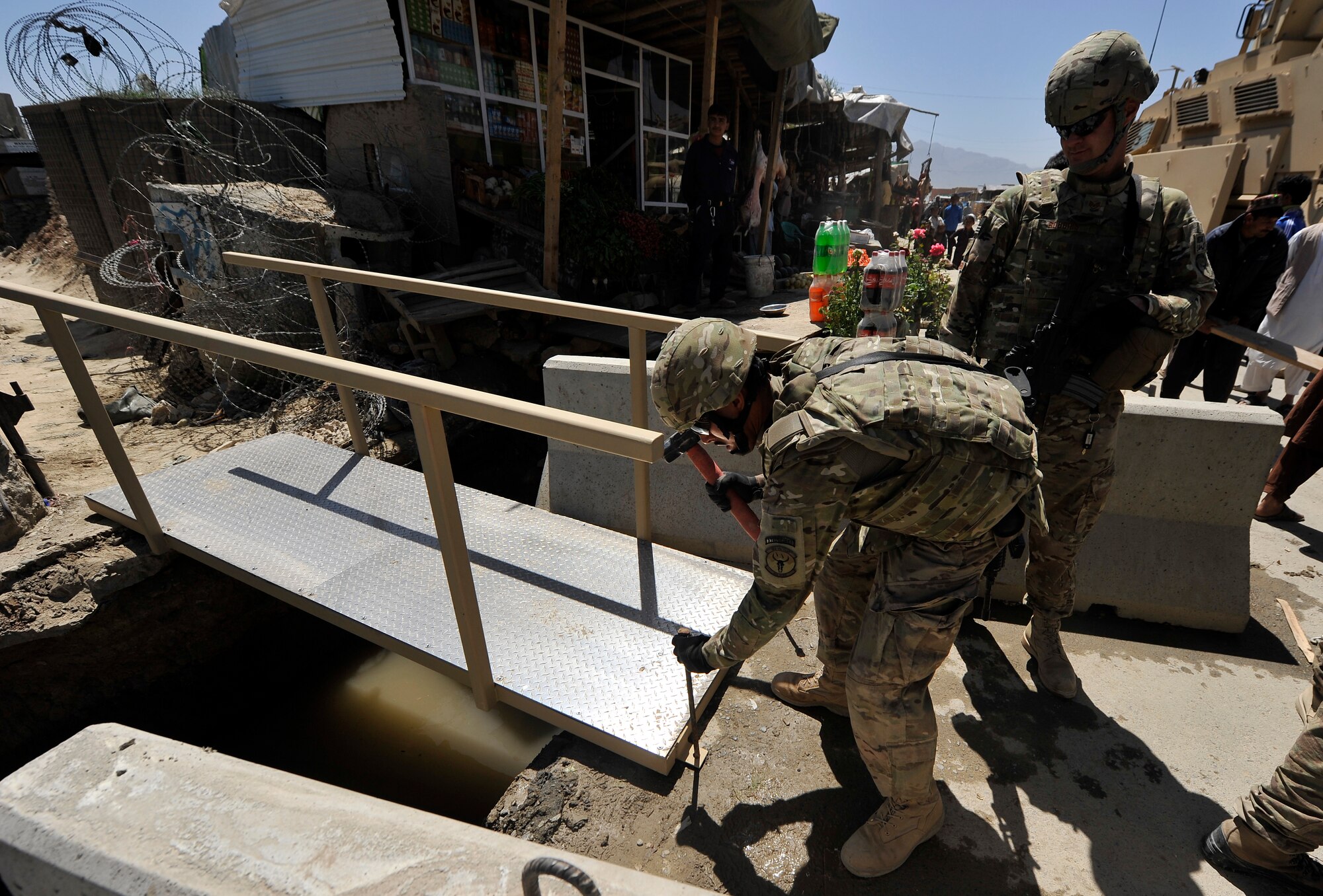 Members of the 455th Expeditionary Civil Engineer Squadron replace the bridges at the entry control point to Bagram Airfield, Afghanistan, May 2, 2013. The 455th ECES structures shop was given a project to construct two bridges to replace the old and rotting matting and wooden planks that went over a flowing river that divided the airfield and the town outside the gates.  (U.S. Air Force photo/Senior Airman Chris Willis)