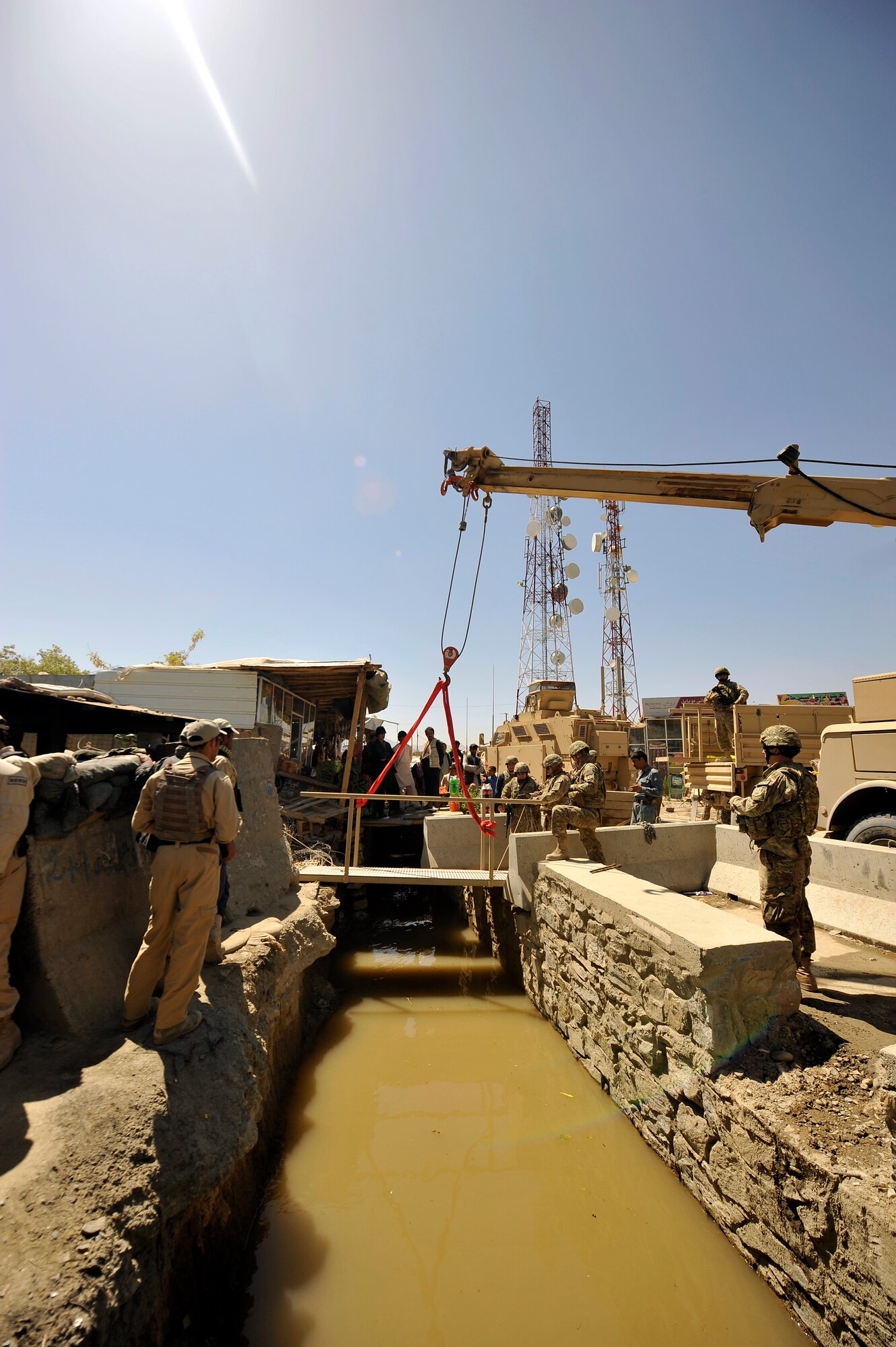 Members of the 455th Expeditionary Civil Engineer Squadron replace the bridges at the entry control point to Bagram Airfield, Afghanistan, May 2, 2013. The 455th ECES structures shop was given a project to construct two bridges to replace the old and rotting matting and wooden planks that went over a flowing river that divided the airfield and the town outside the gates.  (U.S. Air Force photo/Senior Airman Chris Willis)