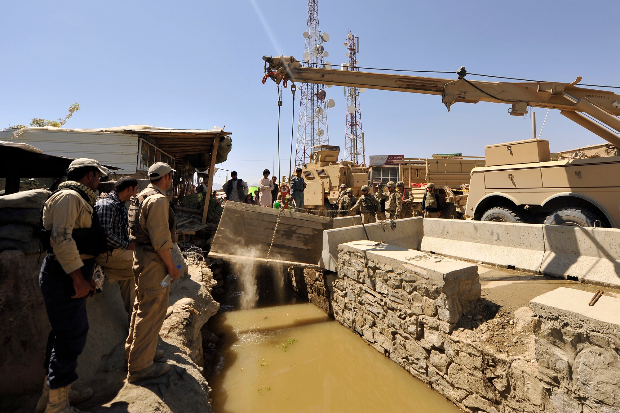 Members of the 455th Expeditionary Civil Engineer Squadron replace the bridges at the entry control point to Bagram Airfield, Afghanistan, May 2, 2013. The 455th ECES structures shop was given a project to construct two bridges to replace the old and rotting matting and wooden planks that went over a flowing river that divided the airfield and the town outside the gates.  (U.S. Air Force photo/Senior Airman Chris Willis)