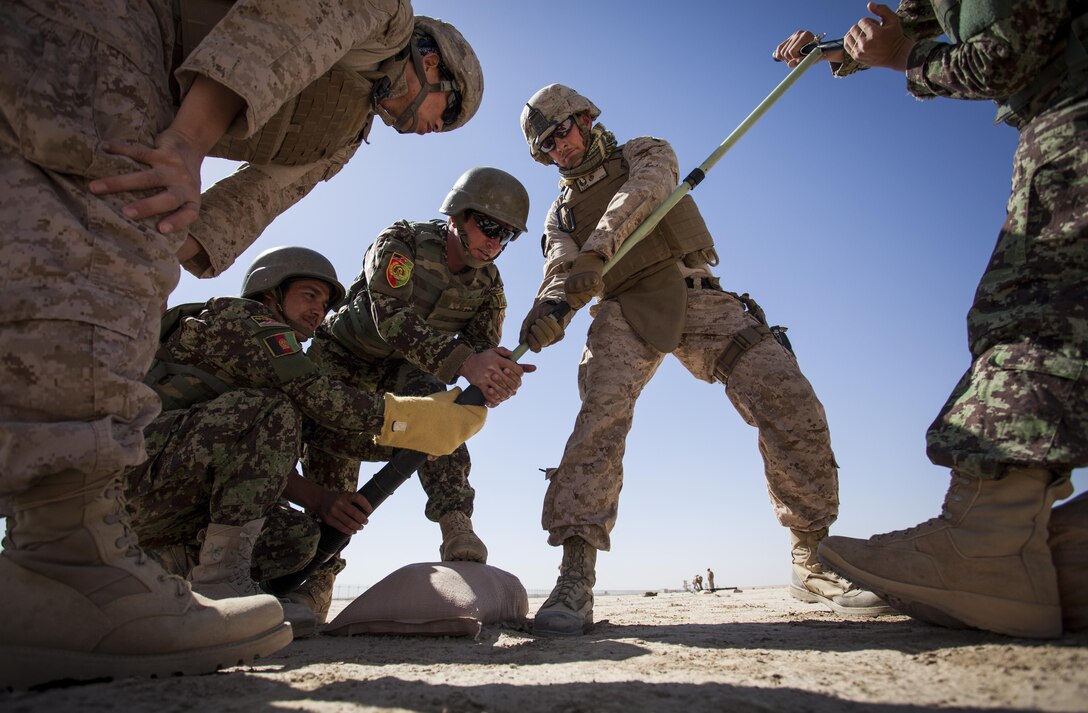 U.S. Marine Corps Staff Sgt. David Denseley, center, from Salt Lake City, Utah, with to the Regional Corps Battle School (RCBS) assists the Afghan National Army (ANA) mortarmen clean out the bore of a 60mm mortar at a mortar range near Camp Shorabak, Helmand province, Afghanistan, May 4, 2013. The Marines with RCBS trained the ANA soldiers to improve on their proficiency with the 60mm mortar weapons system. (U.S. Marine Corps photo by Staff Sgt. Ezekiel R. Kitandwe/Released)