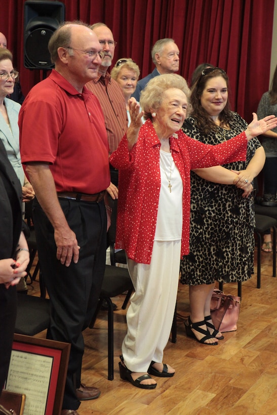 World War II veteran and “frustrated writer,” Amelie Prados Cressend raises her hands in admiration and gratitude as Marine Corps Band New Orleans performed the rearranged, updated and expanded arrangement of Cressend’s original song, “Keep America Free,” at the Marine Corps Support Facility band hall, May 6. Retired Marine Corps musician, former Staff Sgt. Jake Johnson, and Marine Corps Band New Orleans worked together  to bring Cressend’s dream and musical vision to life by harmonizing and rearranging her original score and adapting the song into their official repertoire.