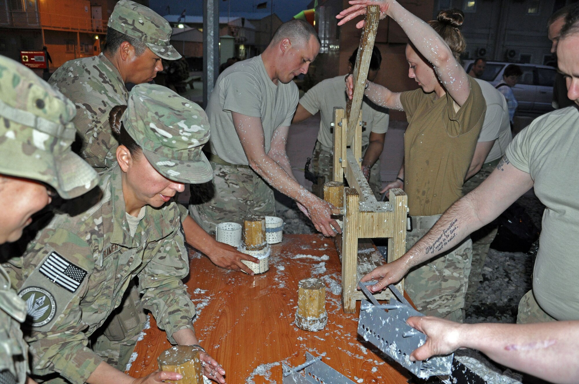 Members of NATO Air Training Command-Afghanistan work together to make fuel pucks and bricks at Kabul International Airport, Afghanistan May 3, 2013. As part of Operation Outreach, a community service organization, members of NATC-A spend every Friday and Saturday evening turning shredded paper, sawdust and water into pucks and bricks that are donated around Kabul and can provide fuel for up to 20 or 40 minutes respectively. (U.S. Air Force photo/ Staff Sgt. Jordan Nestor)