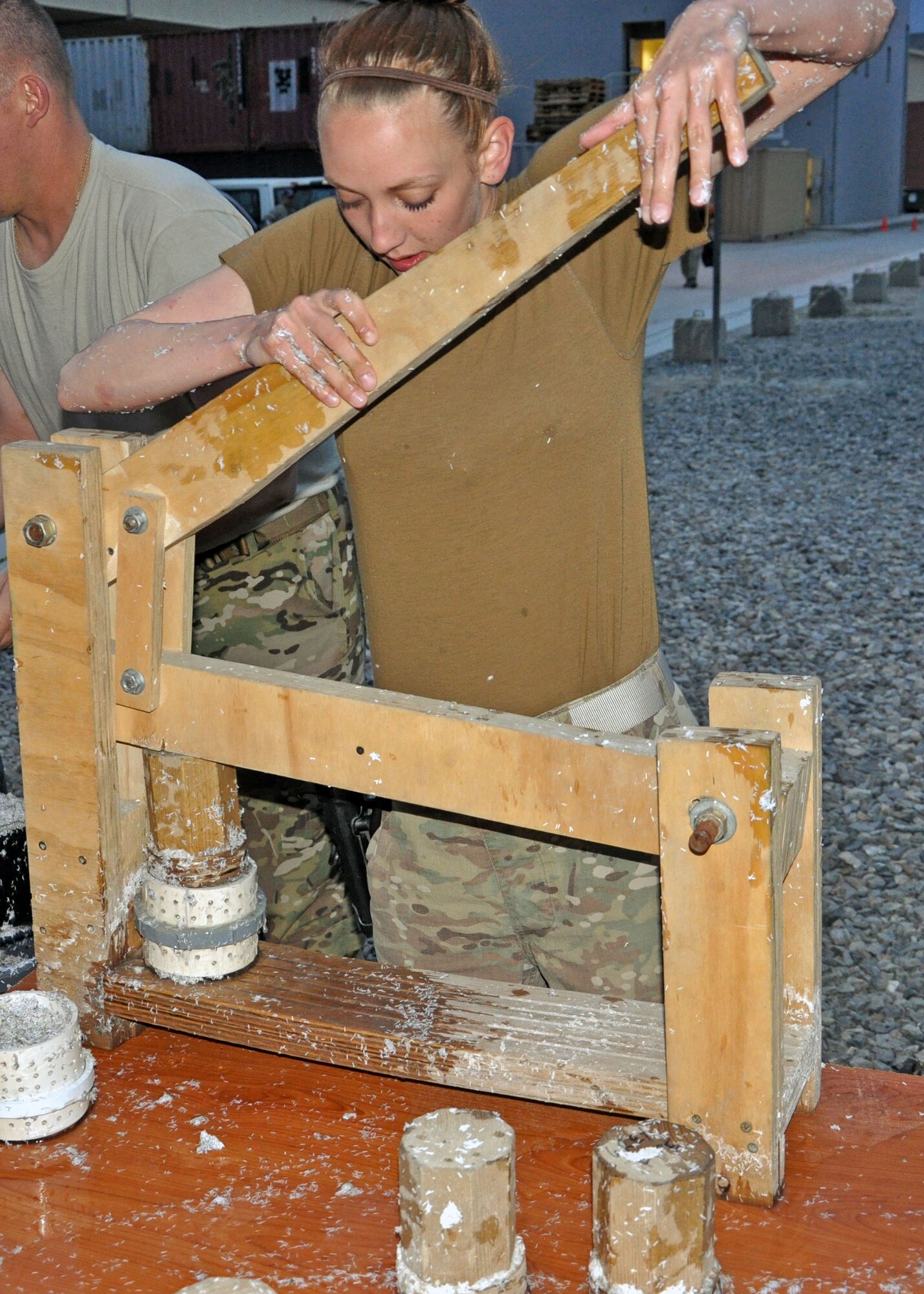 Airman 1st Class Melissa Bradley, 439th Air Expeditionary Advisory Squadron, uses a press created by members of NATC-A to squeeze excess water out of molds to make fuel pucks and Kabul International Airport, Afghanistan May 3, 2013. As part of Operation Outreach, a community service organization, members of NATC-A spend every Friday and Saturday evening turning shredded paper, sawdust and water into pucks and bricks that are donated around Kabul and can provide fuel for up to 20 or 40 minutes respectively. (U.S. Air Force photo/Staff Sgt. Jordan Nestor)