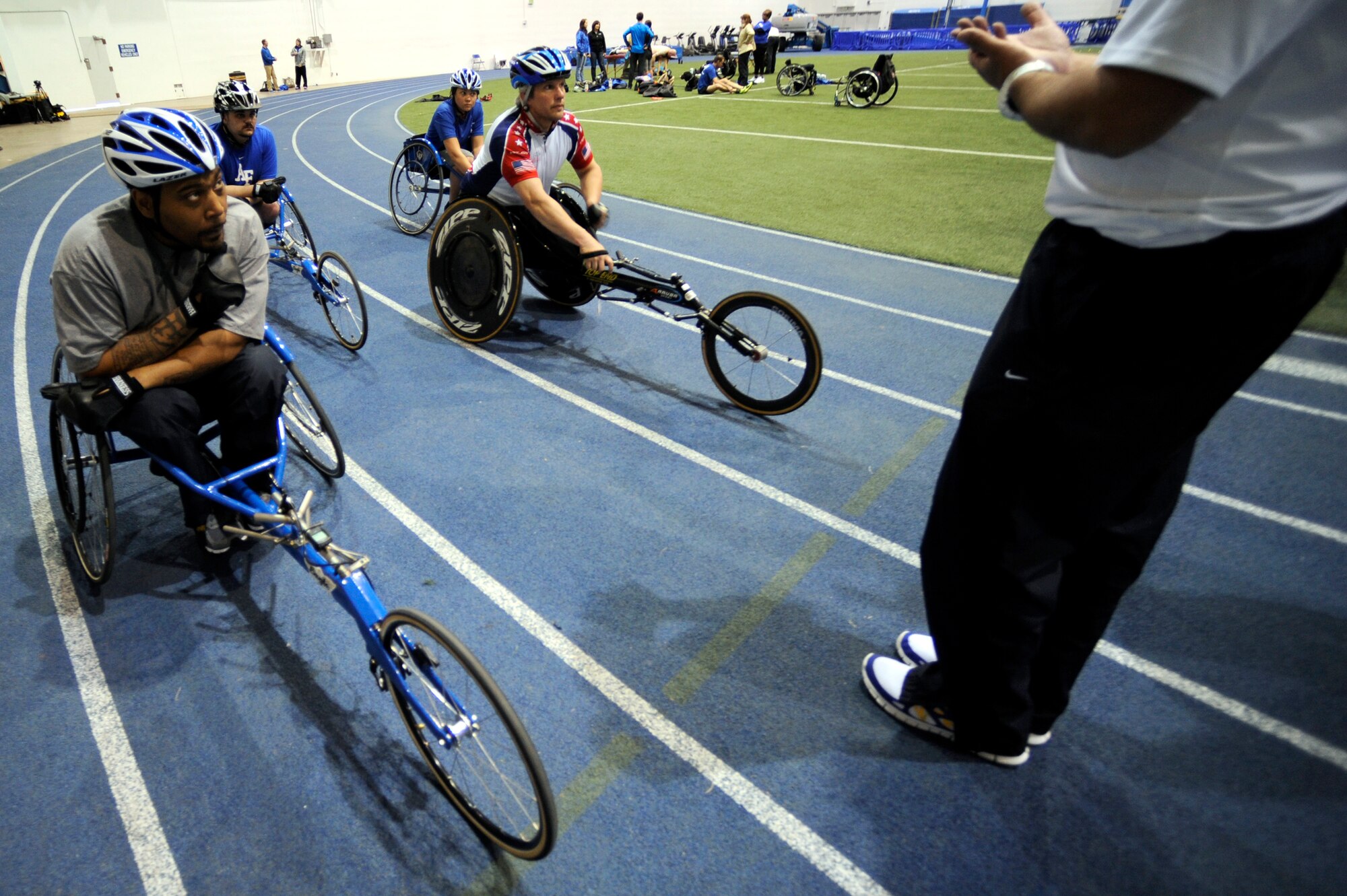 Former Senior Airman Darrell Fisher (left) and his fellow teammates listen to their coach before cycle practice at the U.S. Air Force Academy indoor track during the Air Force's Warrior Games training camp  April 17, 2013, in Colorado Springs, Colo. Fisher served as a jet engine mechanic before he separated from the Air Force. (U.S. Air Force photo/Desiree Palacios)