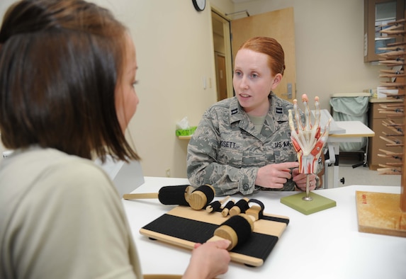 Capt. Jessica San Felippo, 81st Surgical Operations Squadron, demonstrates how to do a functional activity used for hand rehabilitation while Capt. Laura Dossett, 81st MSGS occupational therapist, uses a hand model to show  the muscles and ligaments that the exercise strengthens, May 3, 2013, at the Keesler Medical Center, Keesler Air Force Base, Miss.  Dossett is Keesler’s only occupational therapist and works primarily with arm, wrist and hand ailments that restrict every-day tasks.  (U.S. Air Force photo by Kemberly Groue)
