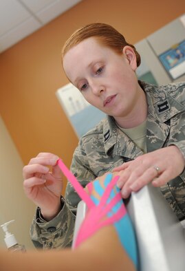 Capt. Laura Dossett, 81st Surgical Operations Squadron occupational therapist, applies kinesio tape on a patient’s arm for edema management May 3, 2013, at the Keesler Medical Center, Keesler Air Force Base, Miss.  Dossett is Keesler’s only occupational therapist and works primarily with arm, wrist and hand ailments that restrict every-day tasks.  (U.S. Air Force photo by Kemberly Groue)