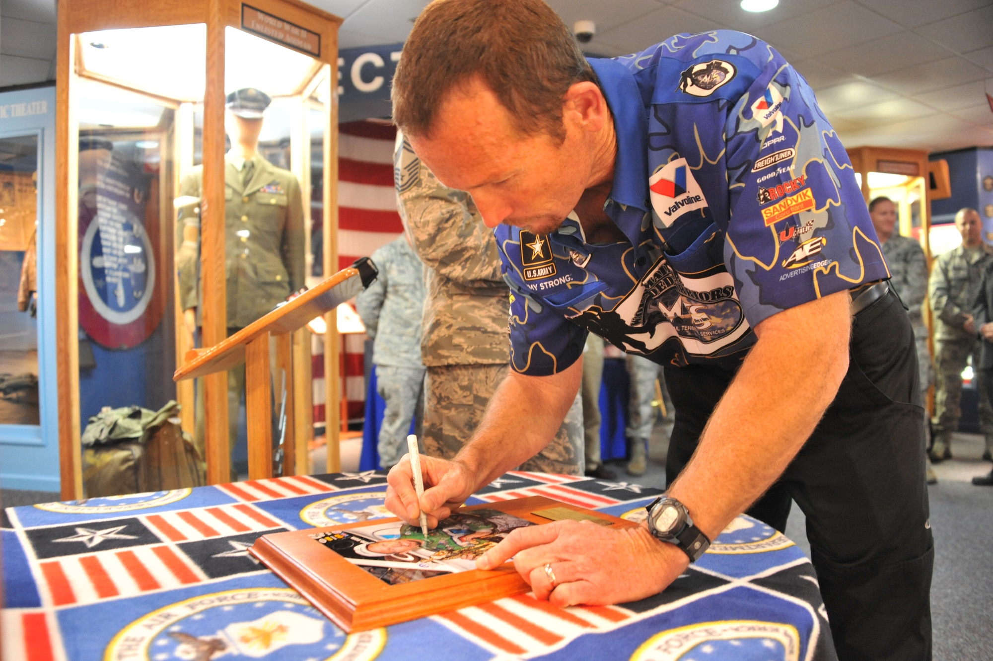 National Hot Rod Association Funny Car champion Jack Beckman signs his photo, after being added to the U.S. Air Force Enlisted Heritage Hall’s Wall of Achievers May 2 at Gunter Annex. The Wall of Achievers pays tribute to former enlisted Airmen who have contributed to the growth and development of the Air Force. (U.S. Air Force photo by Staff Sgt. Sandi Percival)