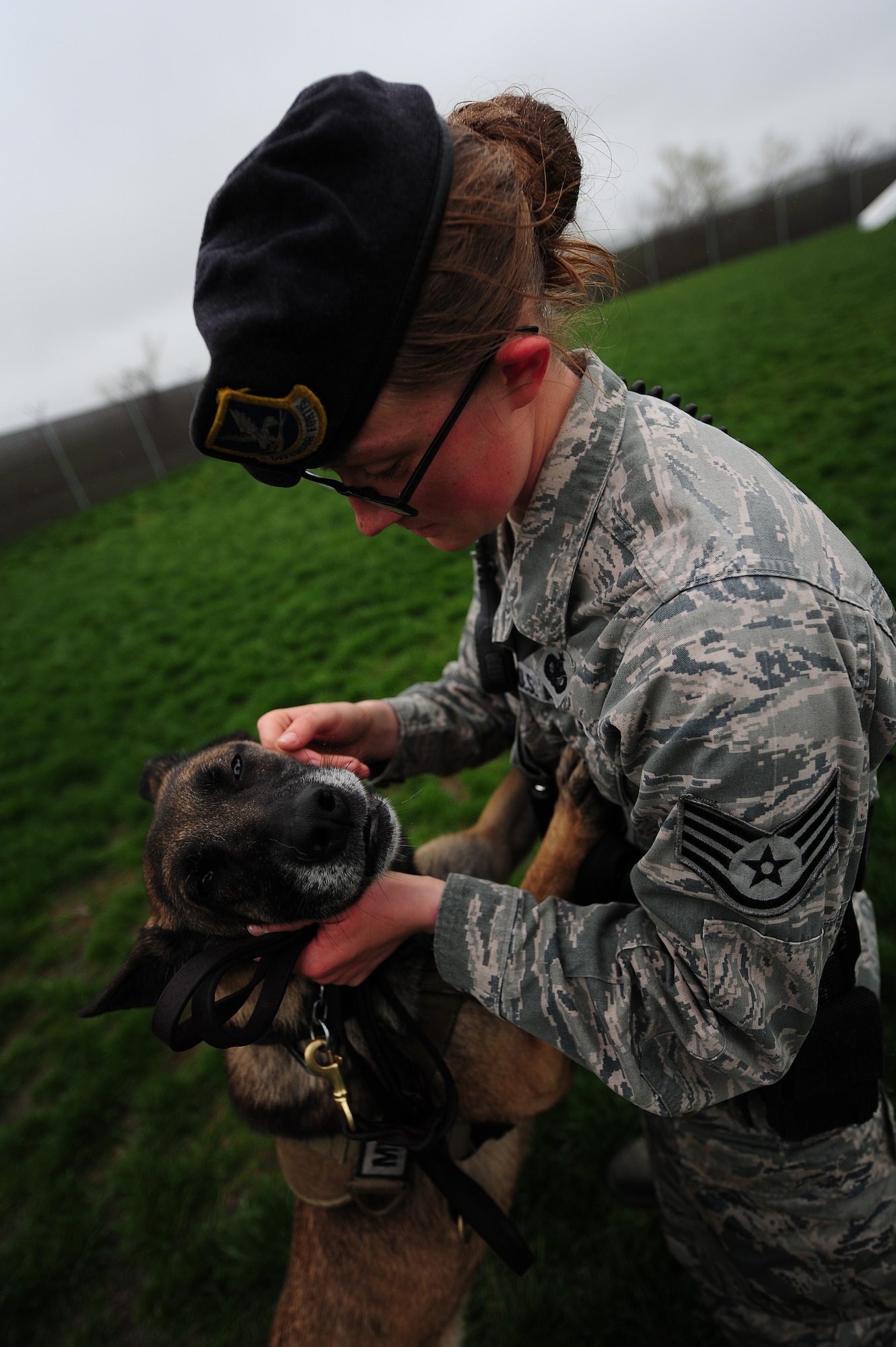 Staff Sgt. Amanda Cubbage, 509th Security Forces Squadron canine handler, pets her dog, Mina, after completing the final stages of a bite sleeve scenario at Whiteman Air Force Base, March 23, 2013. Cubbage conducts various training exercises with Mina everyday to increase levels of trust, confidence and reliability within her assigned canine. (U.S. Air Force photo by Staff Sgt. Nick Wilson/Released)