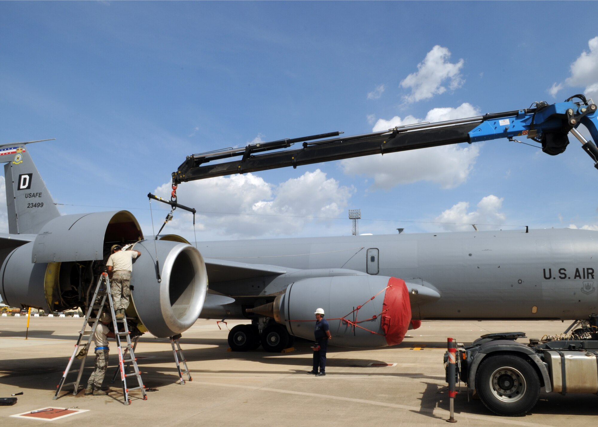 Maintainers and a contractor use a crane to lift the engine ring cowl onto the No. 4 engine of a KC-135R Stratotanker, deployed from the 100th Air Refueling Wing, April 22, 2013, in Southwest Europe. The cowl was removed to allow maintainers deployed with the 351st Expeditionary Air Refueling Squadron to swap a damaged engine out with a replacement. (U.S. Air Force photo by 1st Lt. Christopher Mesnard/Released)